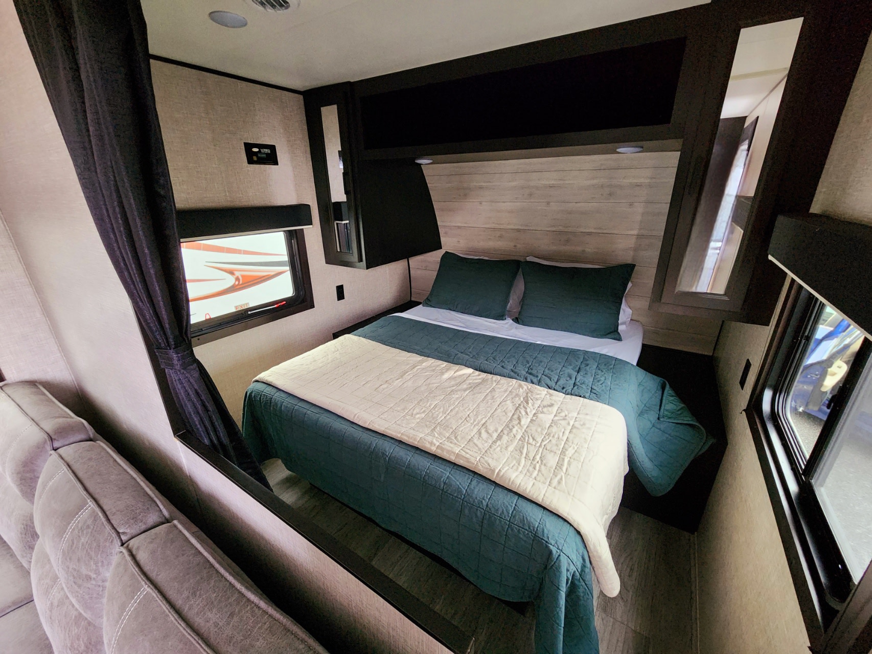 RV rental bedroom with a comfy queen bed, green linens, wood-panel headboard, and ample overhead storage.. Jayco Jay Flight 2023