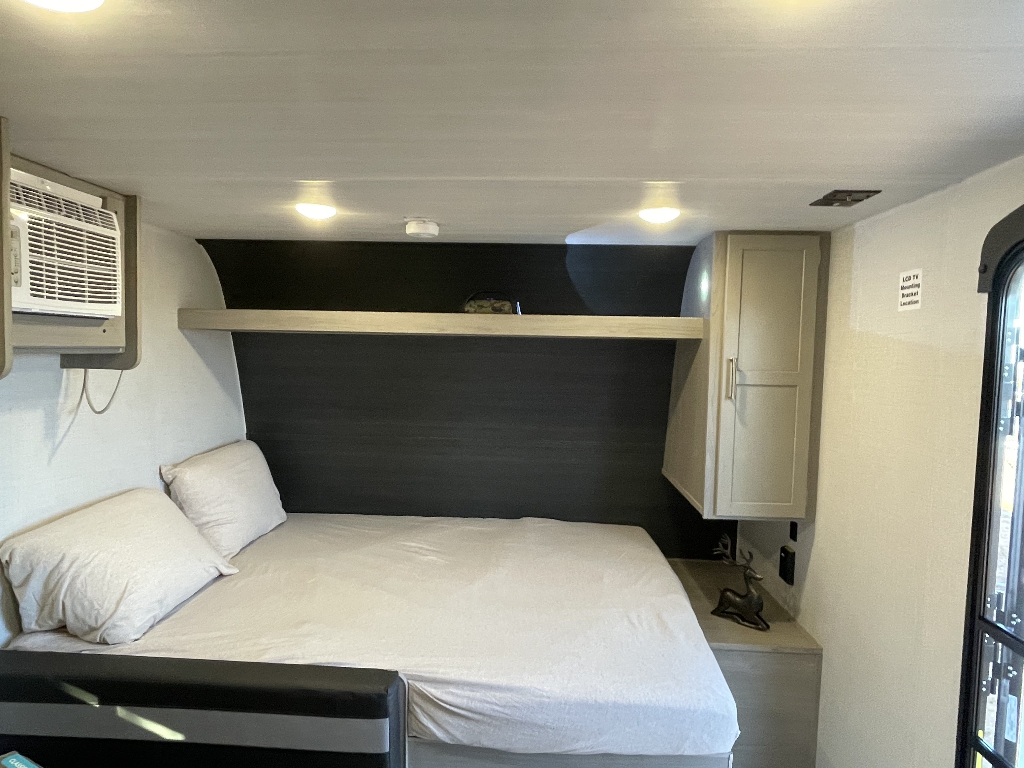 RV rental: Comfortable bedroom featuring a bed, pillows, wall AC, overhead shelf, and storage cabinet for your travels.. Keystone Rv company 1800bh 2024