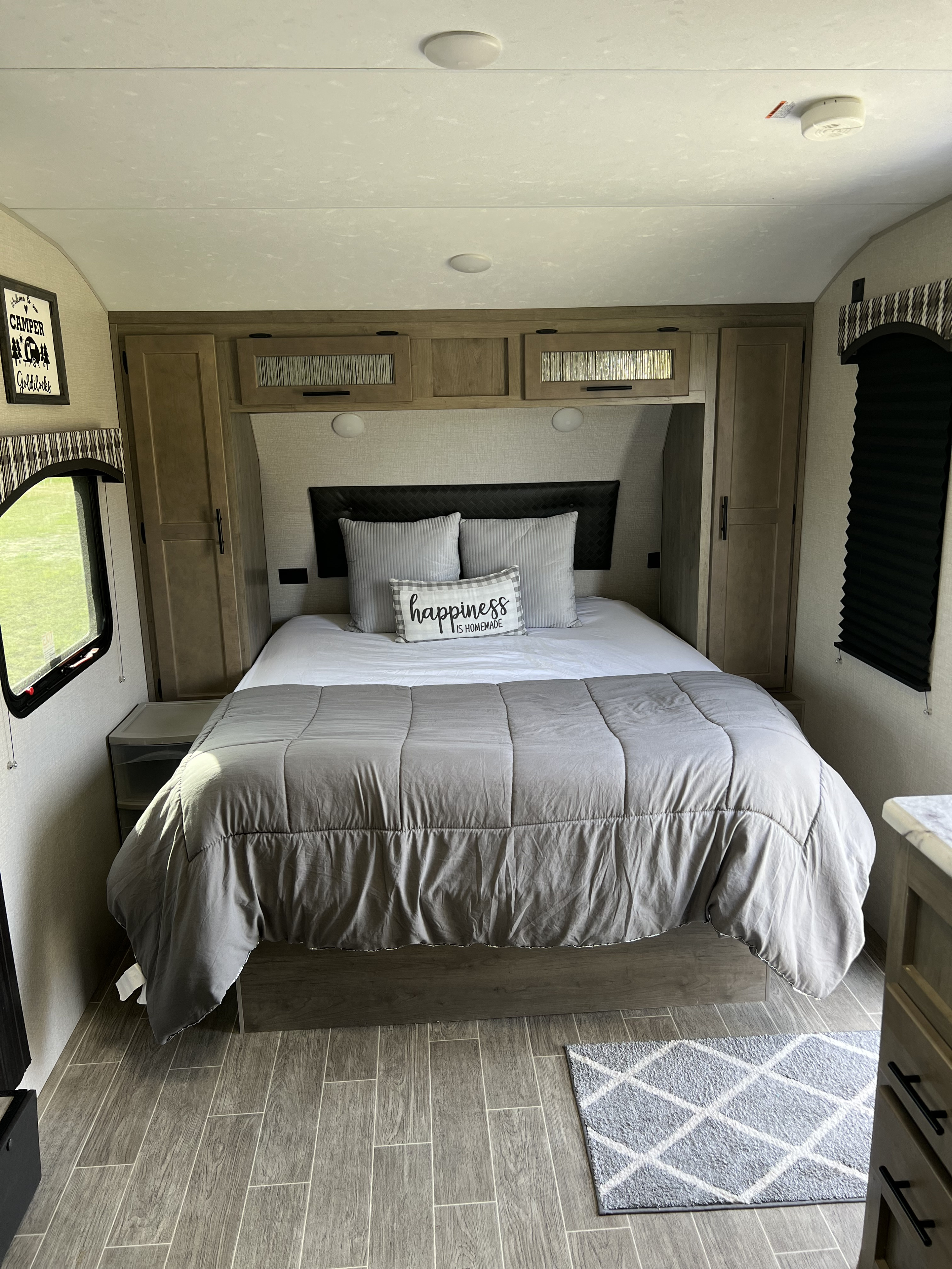 Inviting RV rental camper bedroom with queen bed, cozy gray bedding, wood cabinets, and plank flooring.. Venture Sonic 211VDB 2021