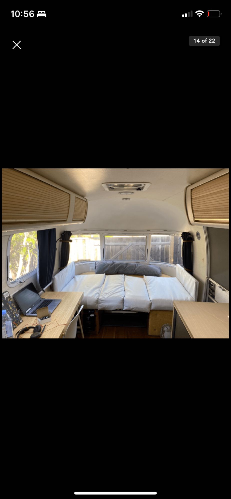 Spacious RV rental interior featuring a convertible bed/seating area and a dedicated desk workstation with a laptop.. Airstream Argosy 1977