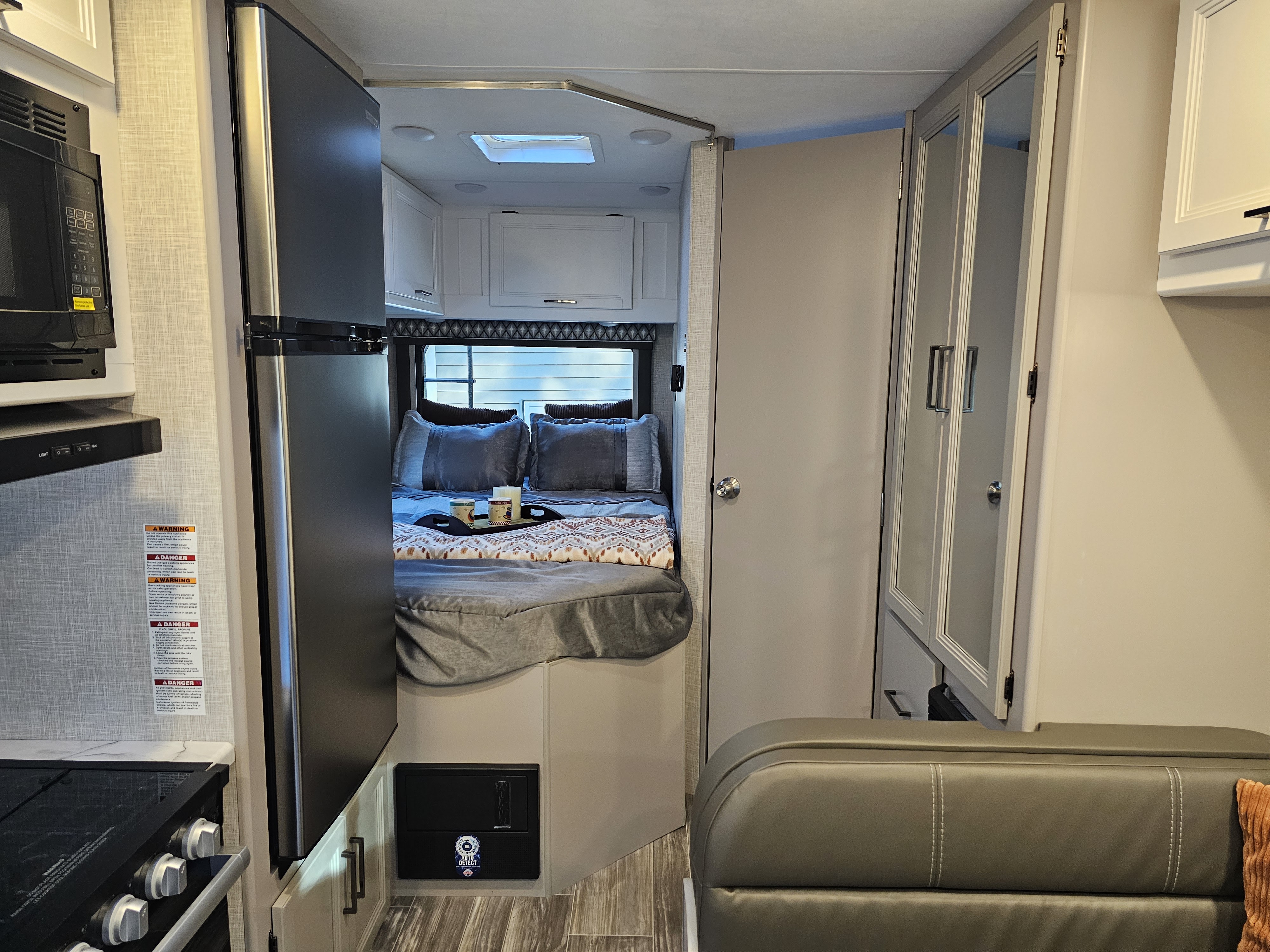 Cozy RV rental interior featuring a compact kitchen, comfortable bedroom, and seating area for your travel adventures.. Other Other 2024