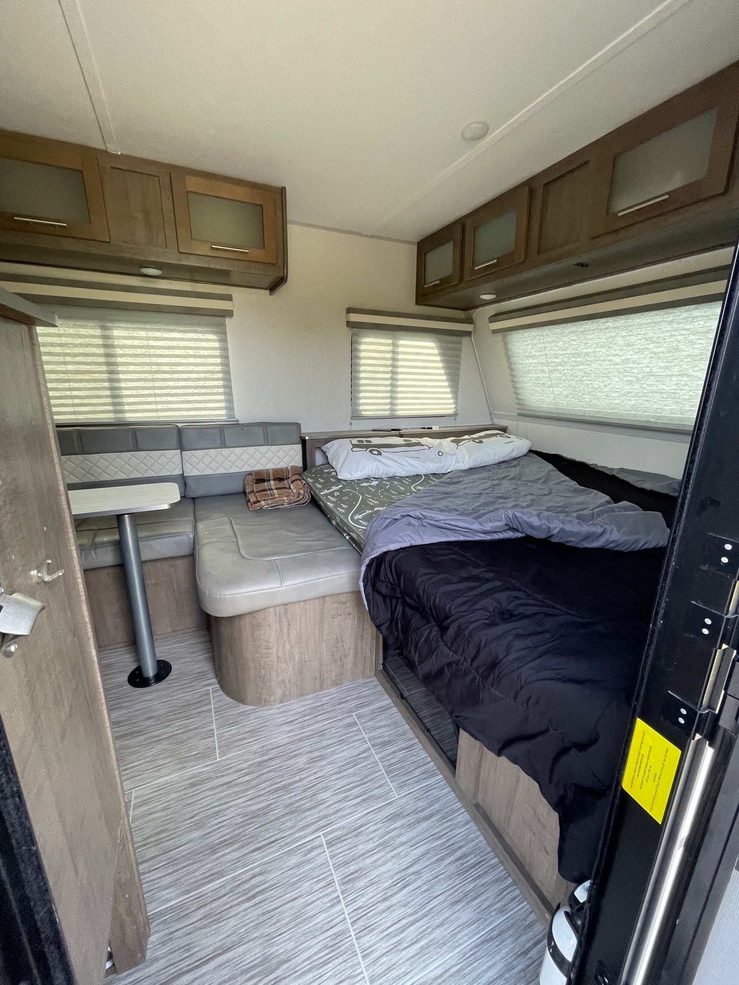 Cozy RV rental interior showing a dinette, bed, and overhead storage, perfect for travel.. Forest River No Boundaries 19.7 2019