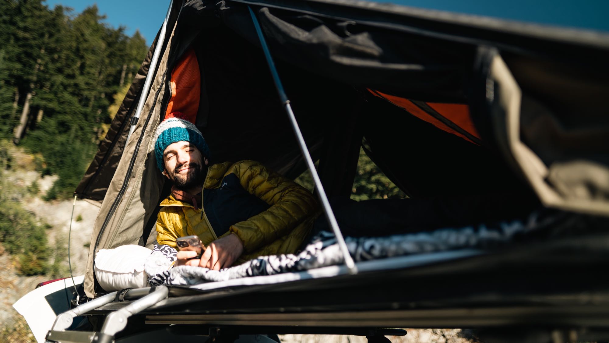Happy man relaxing in an RV rental rooftop tent, enjoying nature's sunlight. Perfect for outdoor adventure.. Dodge Journey 2013