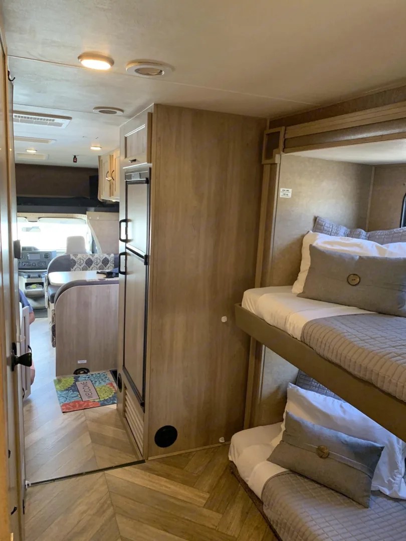 Cozy rv rental interior with bunk beds, refrigerator, and herringbone floor, perfect for family adventures.. Coachmen Freelander 32BH 2016