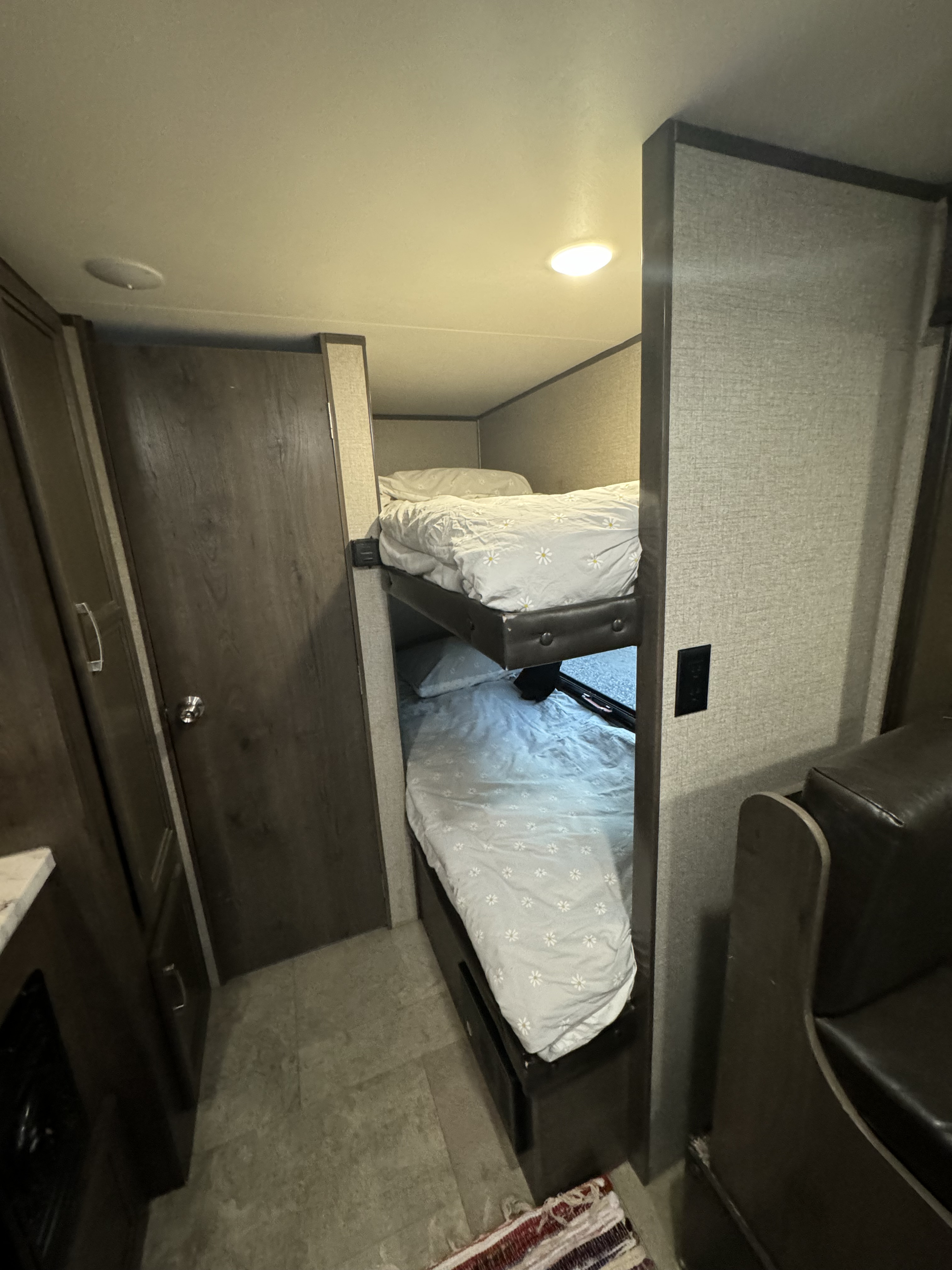 This RV rental features stacked bunk beds with light floral bedding, offering a compact and cozy sleeping area.. Jayco Jay Flight SLX 2020