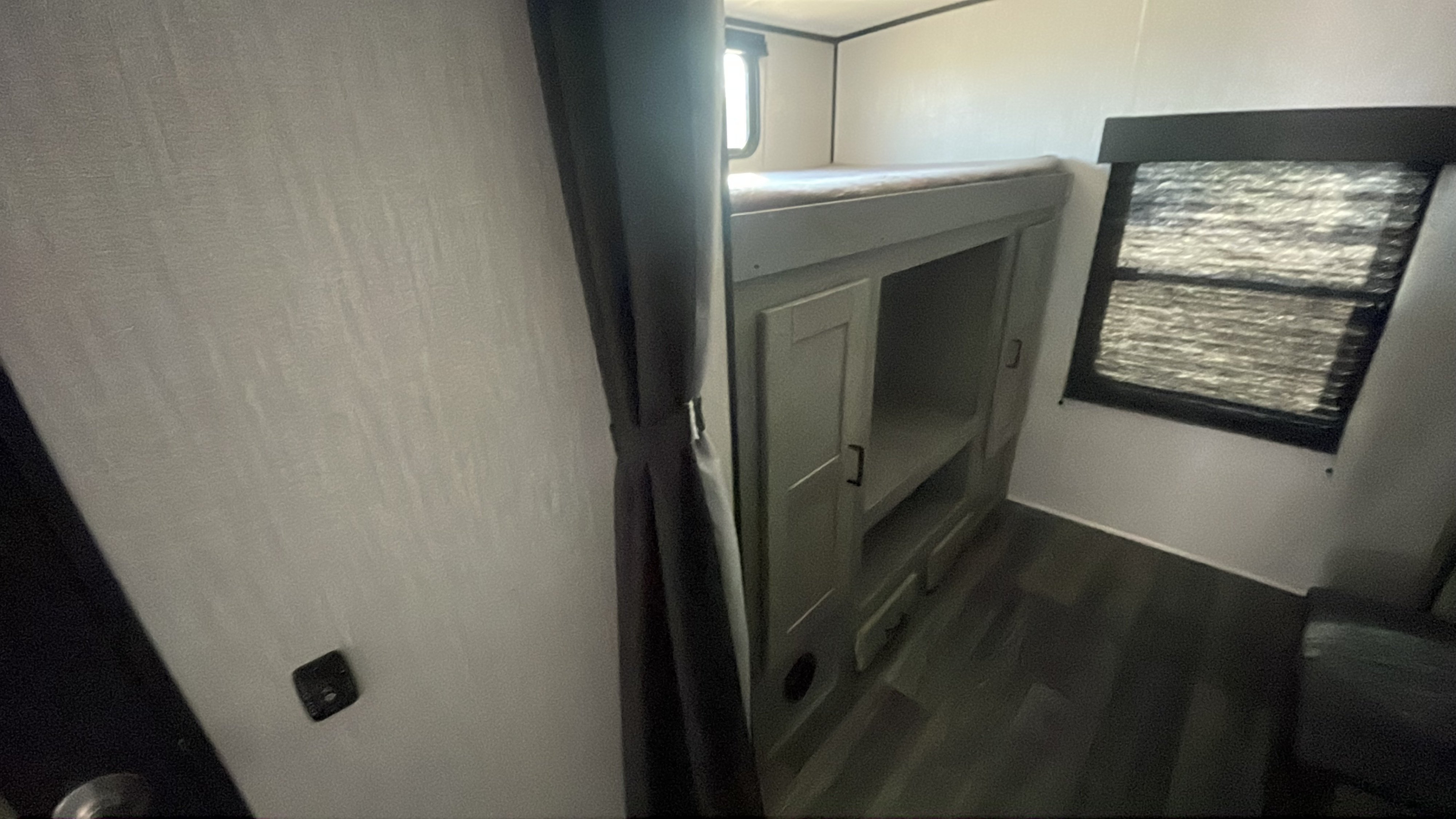 RV rental bunk bed with storage, window, and privacy curtain, designed for efficient compact living space.. Heartland RVs Mallard 2021