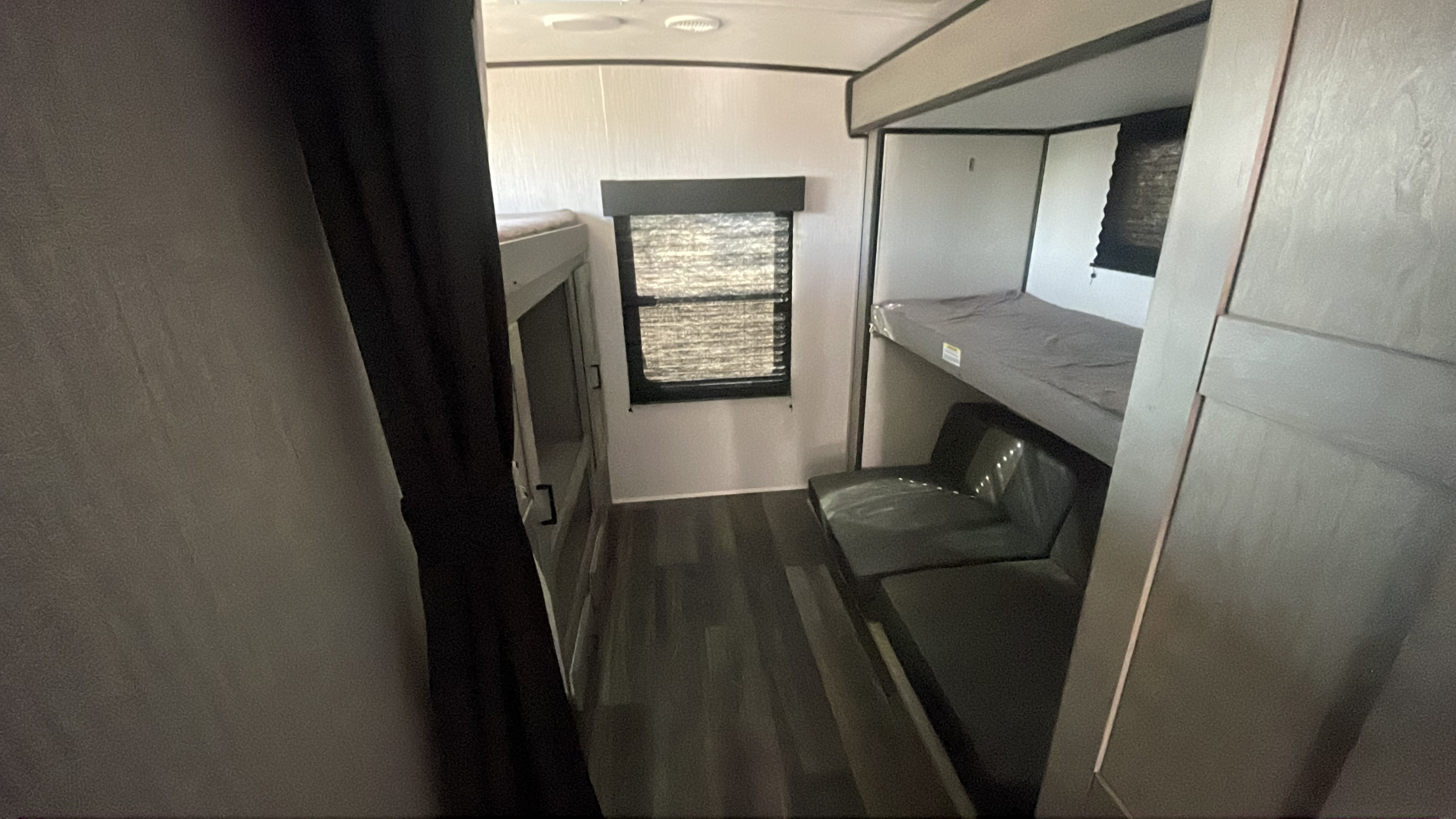 View of an RV rental bunkhouse with two bunk beds and a small sofa. The window offers natural light in this modern camper.. Heartland RVs Mallard 2021