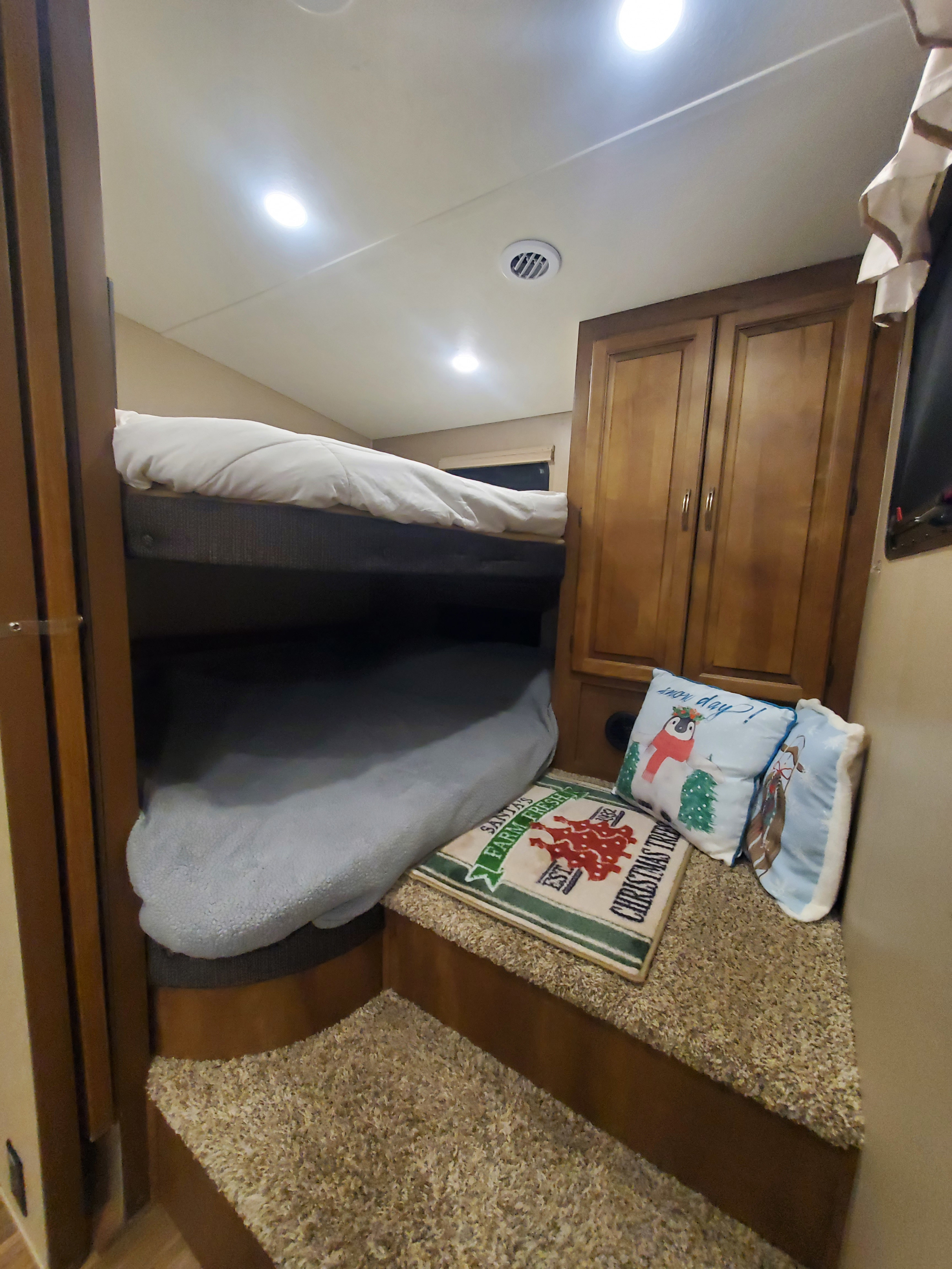 Cozy RV rental bunk beds with wooden cabinets, carpeted steps, and festive holiday decor, ideal for family travel.. Coachman Chapperal 2018