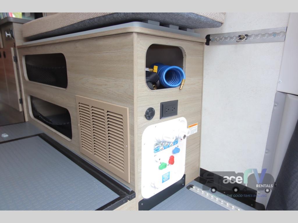 RV rental interior: practical storage, a water utility panel with a hose, and power outlets for convenience.. Winnebago Solis 2021
