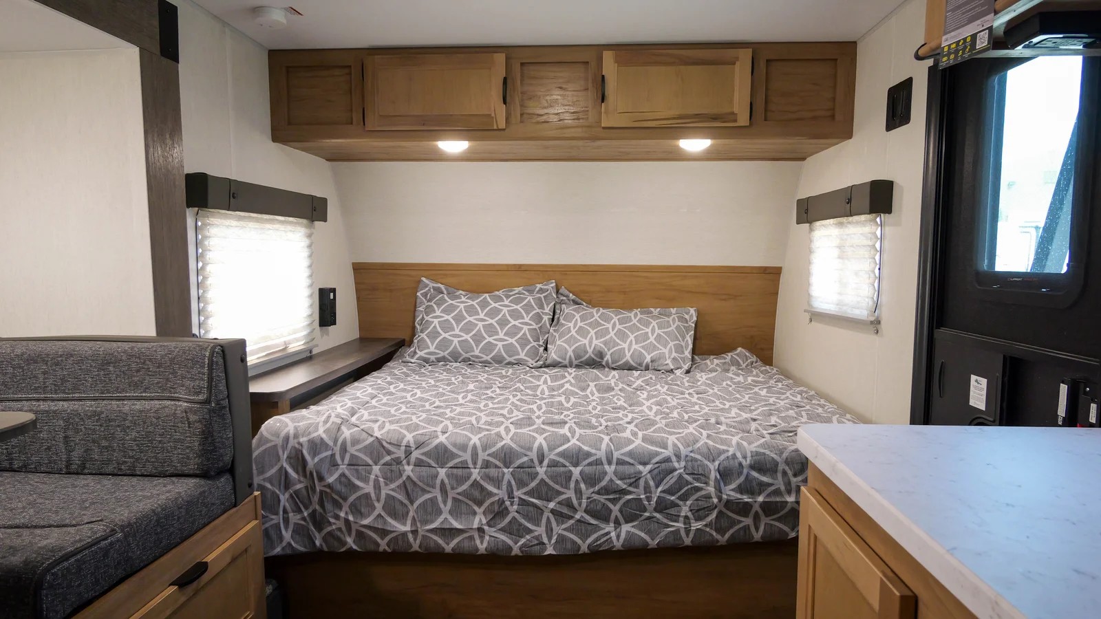 Spacious RV rental bedroom with a comfy bed, wood headboard, cabinets, dinette seat, and counter.. Forest River 19' Bunkhouse with Slide 2024
