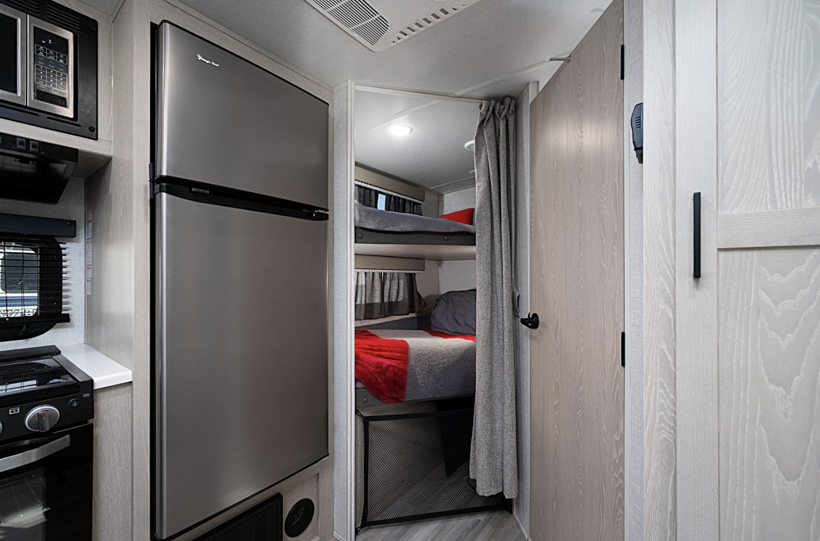 Modern RV rental interior: kitchen with stainless steel fridge, microwave, stove, and cozy bunk beds.. Forest River Flagstaff Micro Lite 2021
