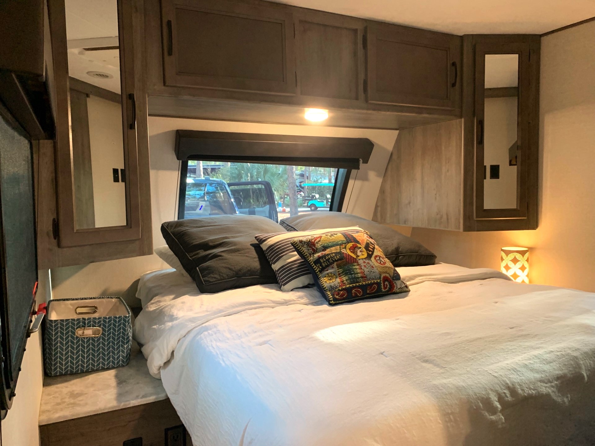 The Master Bedroom is your haven of tranquility and boasts a dedicated A/C unit, ensuring your personalized comfort. Slide the door shut for complete privacy. Gaze out the expansive picture window, bringing the beauty of the outdoors inside. Privacy blinds offer the option for complete seclusion, allowing you to unwind and truly disconnect. The crisp, fresh linens invite you to sink into restful slumber. This master bedroom becomes a haven for relaxation and rejuvenation. Coachmen Apex 2021