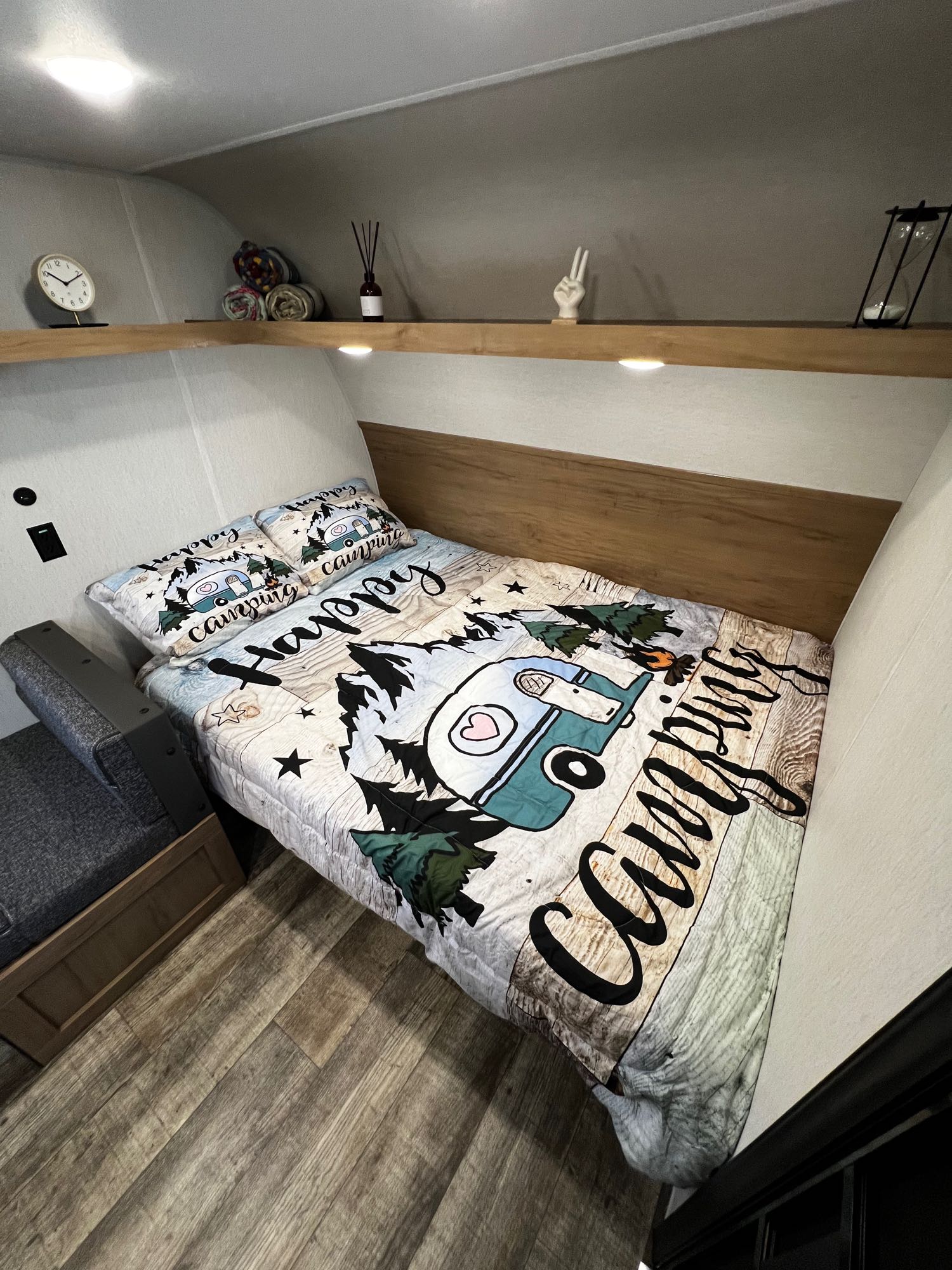 Cozy RV rental bedroom with "Happy Camping" bedding & shelf decor for your adventure.. Forest River Wolf Den 16EV 2024