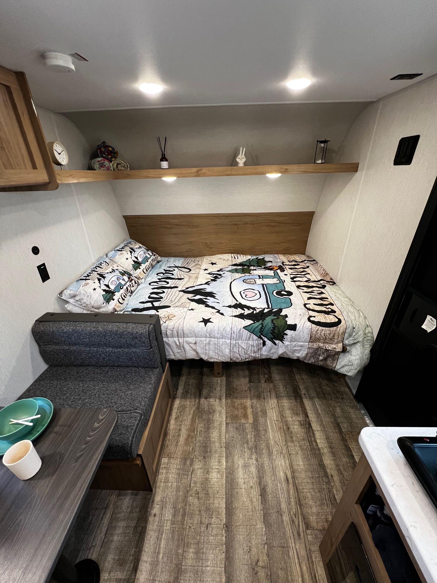 This RV rental interior features a cozy bed with themed bedding, a dinette, and a compact kitchen area.. Forest River Wolf Den 16EV 2024