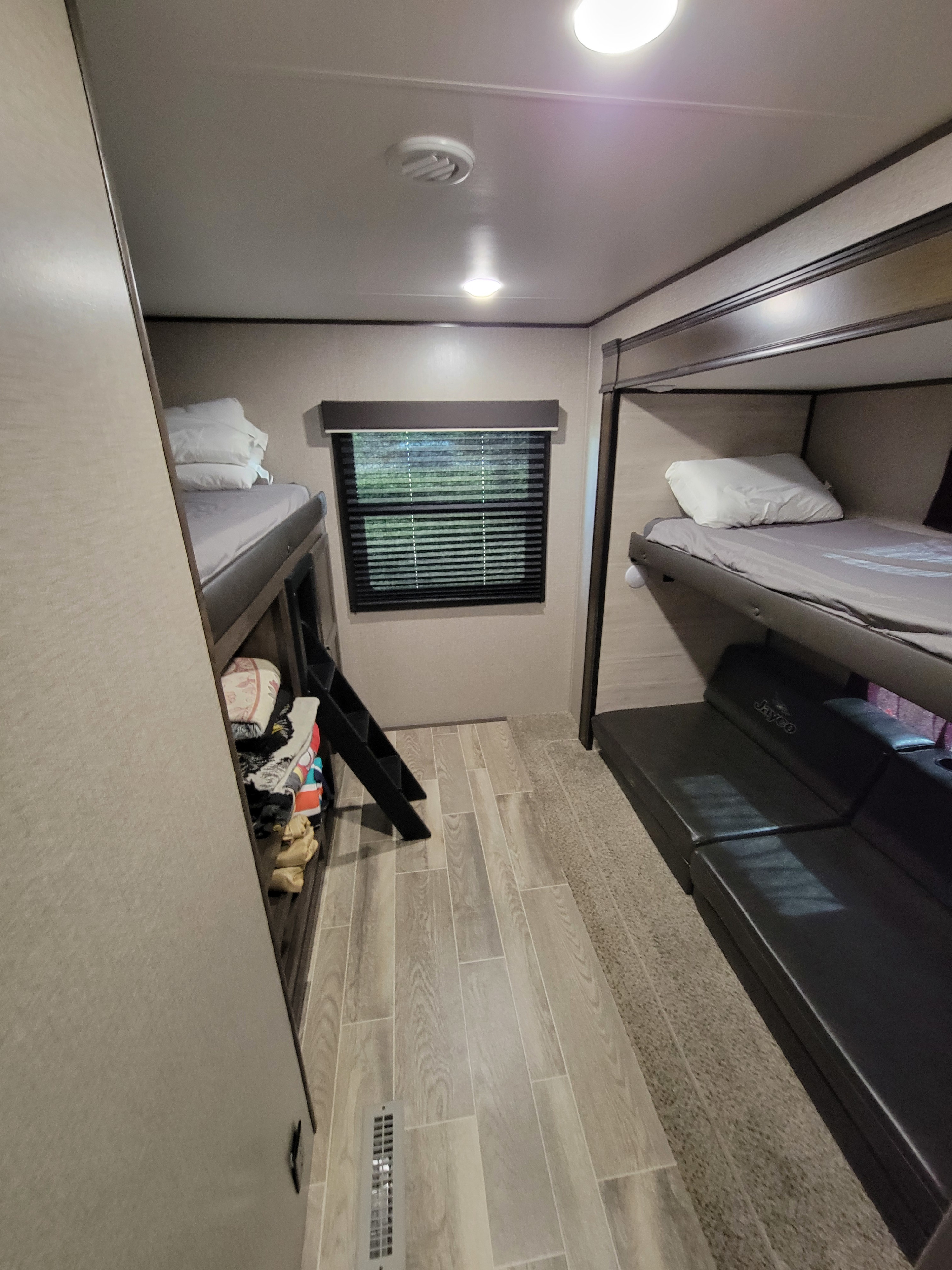 Bright RV rental bunkhouse showing sleeping bunks, a convertible sofa, and a mix of wood-look and carpet flooring.. Jayco Jay Flight SLX 2021