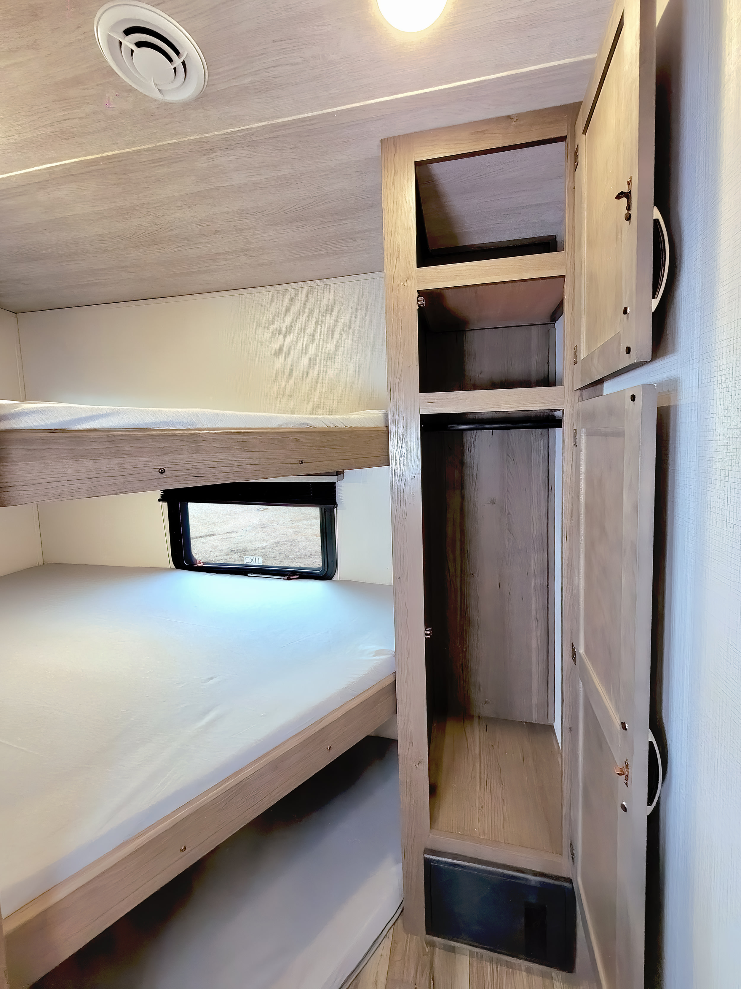 This RV rental features stacked bunk beds, a window, and a built-in wardrobe, offering comfortable and practical sleeping space.. Keystone RV Cougar 2023