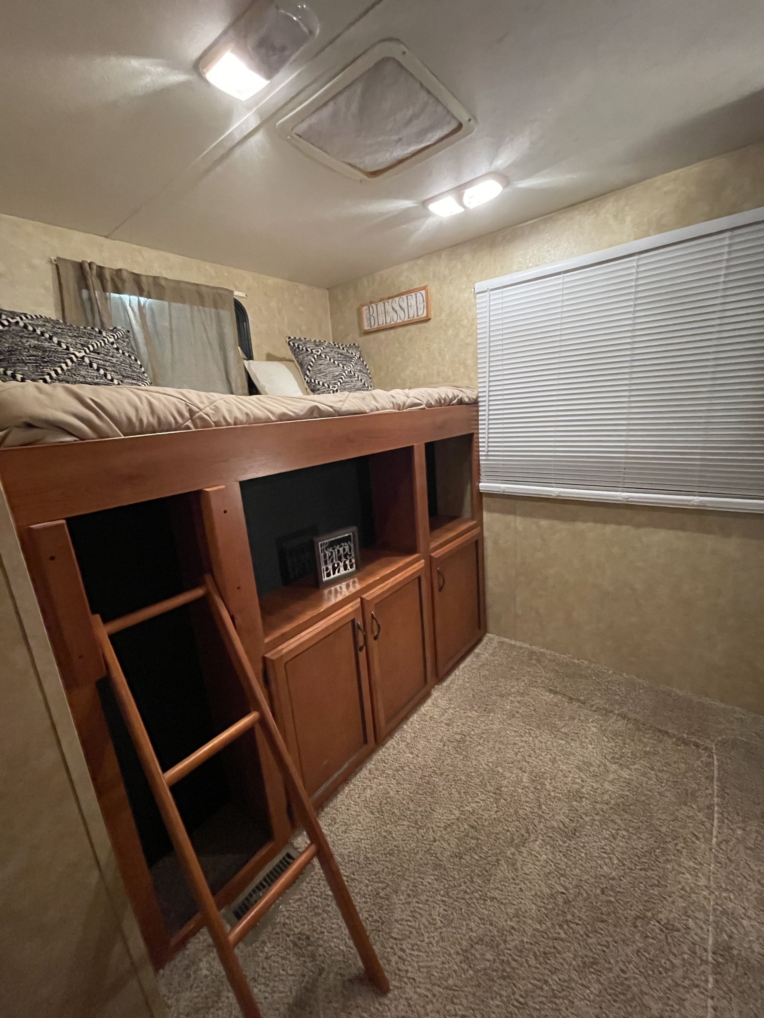 Cozy RV bunk bed with ladder, storage, windows, and carpeted floor. Ideal for rv rental travelers.. Coachman Catalina 2010