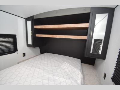 Comfortable RV rental bedroom with a spacious bed, overhead shelves, and mirrored storage cabinets.. Keystone SPRINGDALE 2022