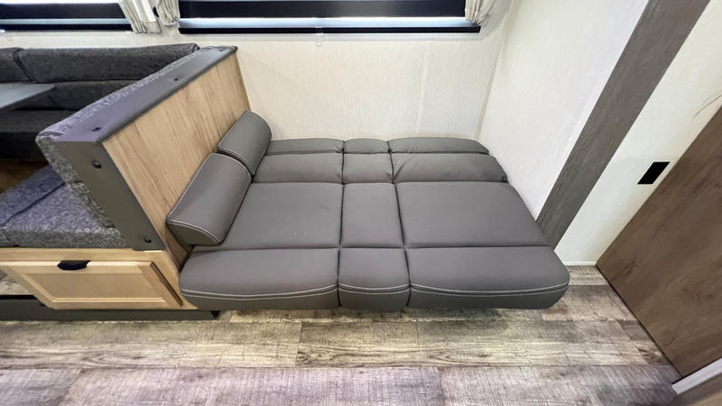 RV rental interior: A versatile grey cushioned dinette converts into a comfortable bed for optimal space.. Forest River 28' Bunkhouse with Slide 2024