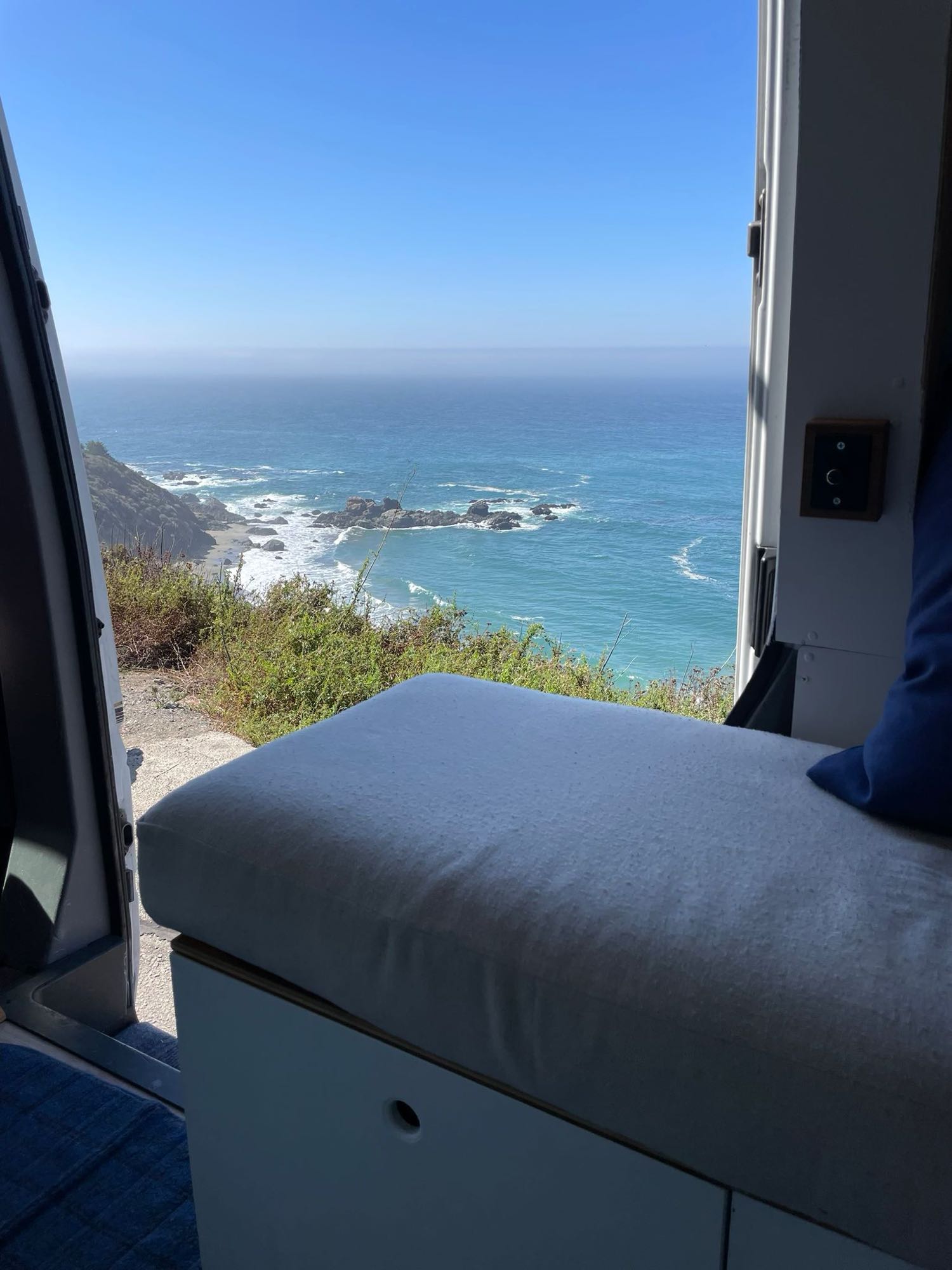 Ocean vista from an RV rental van, showing a rocky coast & blue sea from inside the comfortable camper.. Dodge Sprinter Wagon 2500 2003