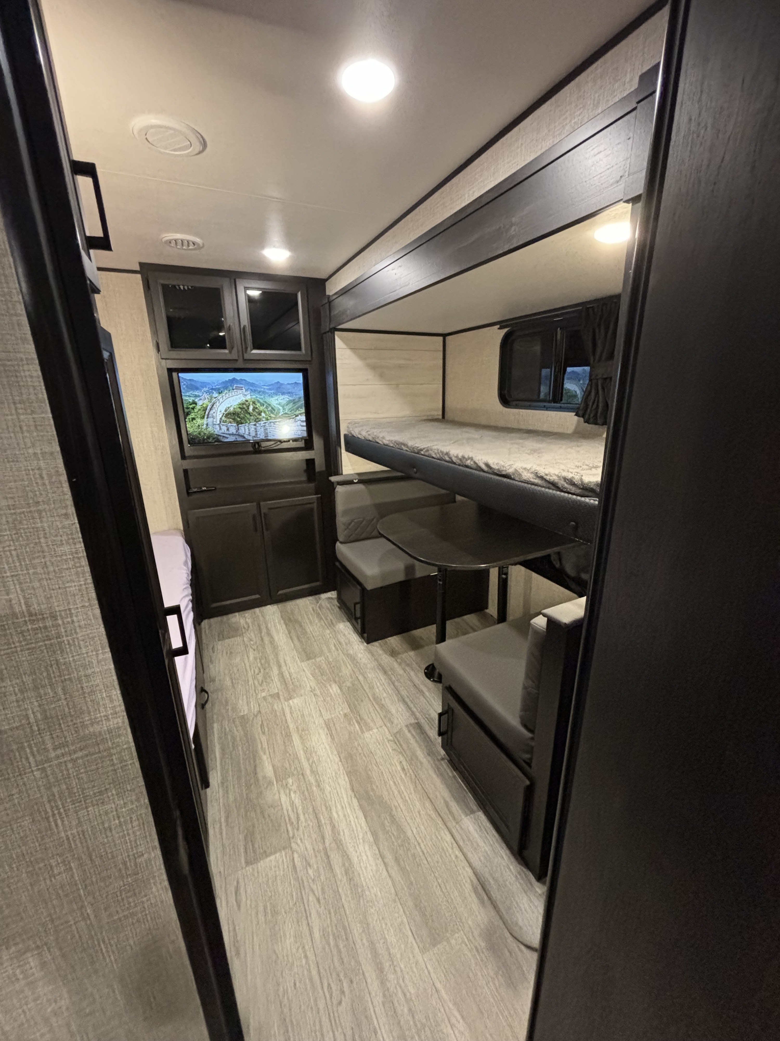 Cozy RV rental interior with bunk beds, dinette, TV, and light wood flooring, offering comfortable living space.. Jayco Jay Flight 2023