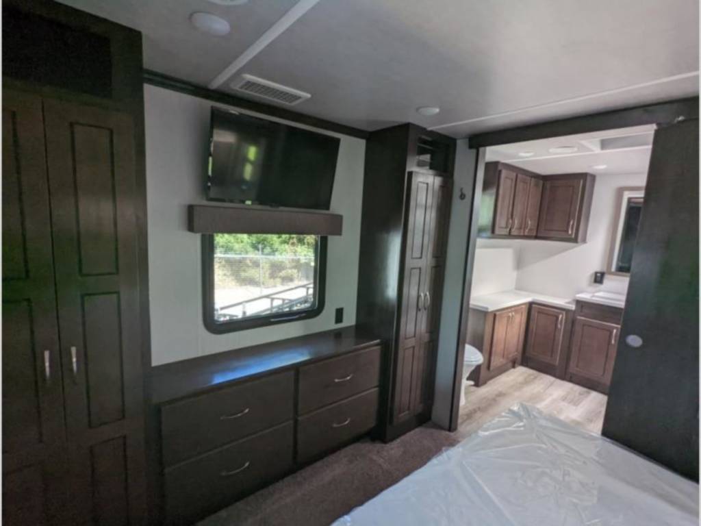 Spacious RV rental: well-appointed bedroom with ample storage & TV, plus a connected, modern full bathroom.. Cedar Creek Silverback 2021