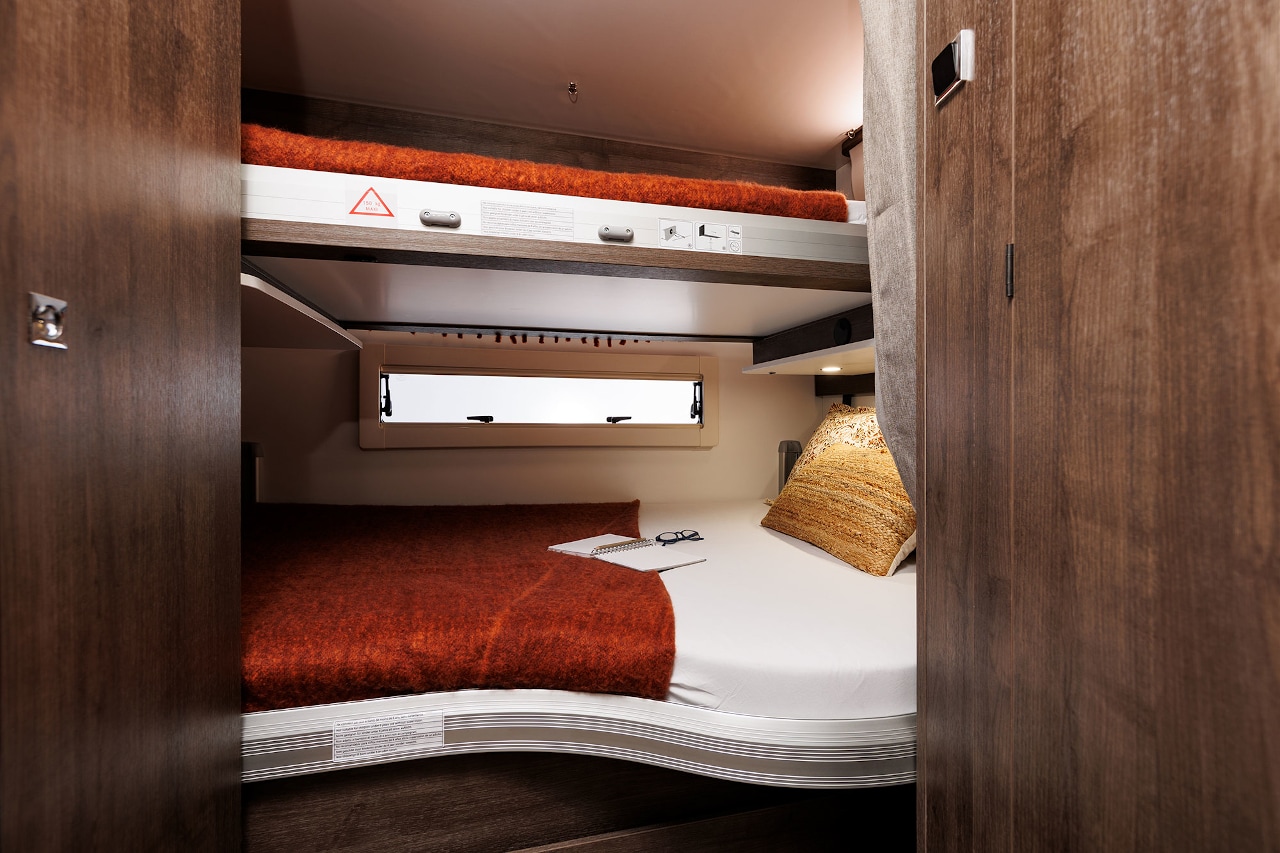 Inside this RV rental: a cozy, well-lit sleeping area featuring lower and upper bunk beds, perfect for trips.. Benimar Sport 340 UP 2024