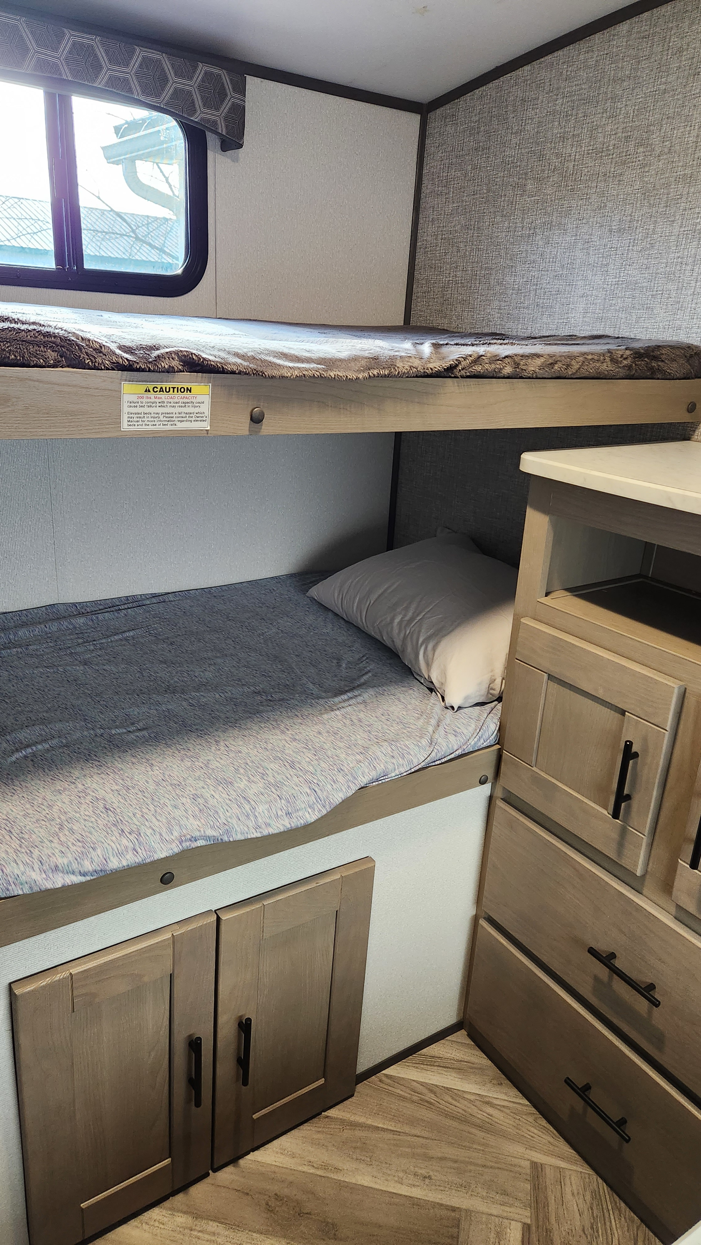 This RV rental features cozy bunk beds with built-in storage and a window, ideal for compact travel.. Cruiser RV Shadow Cruiser 2021