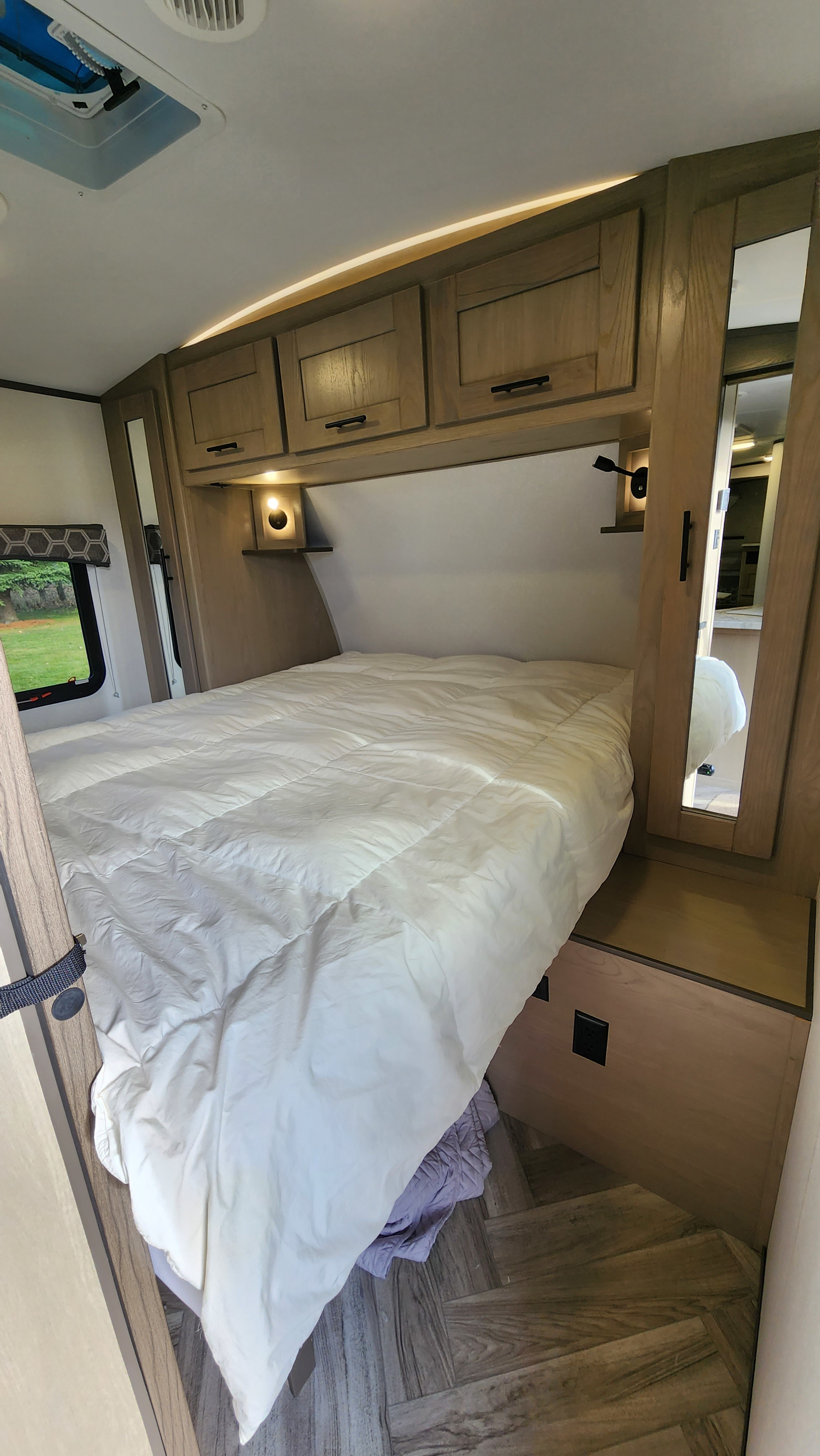 Comfortable RV rental bedroom with a large bed, wooden overhead cabinets, and soft ambient lighting. Ready for travel!. Cruiser RV Shadow Cruiser 2021