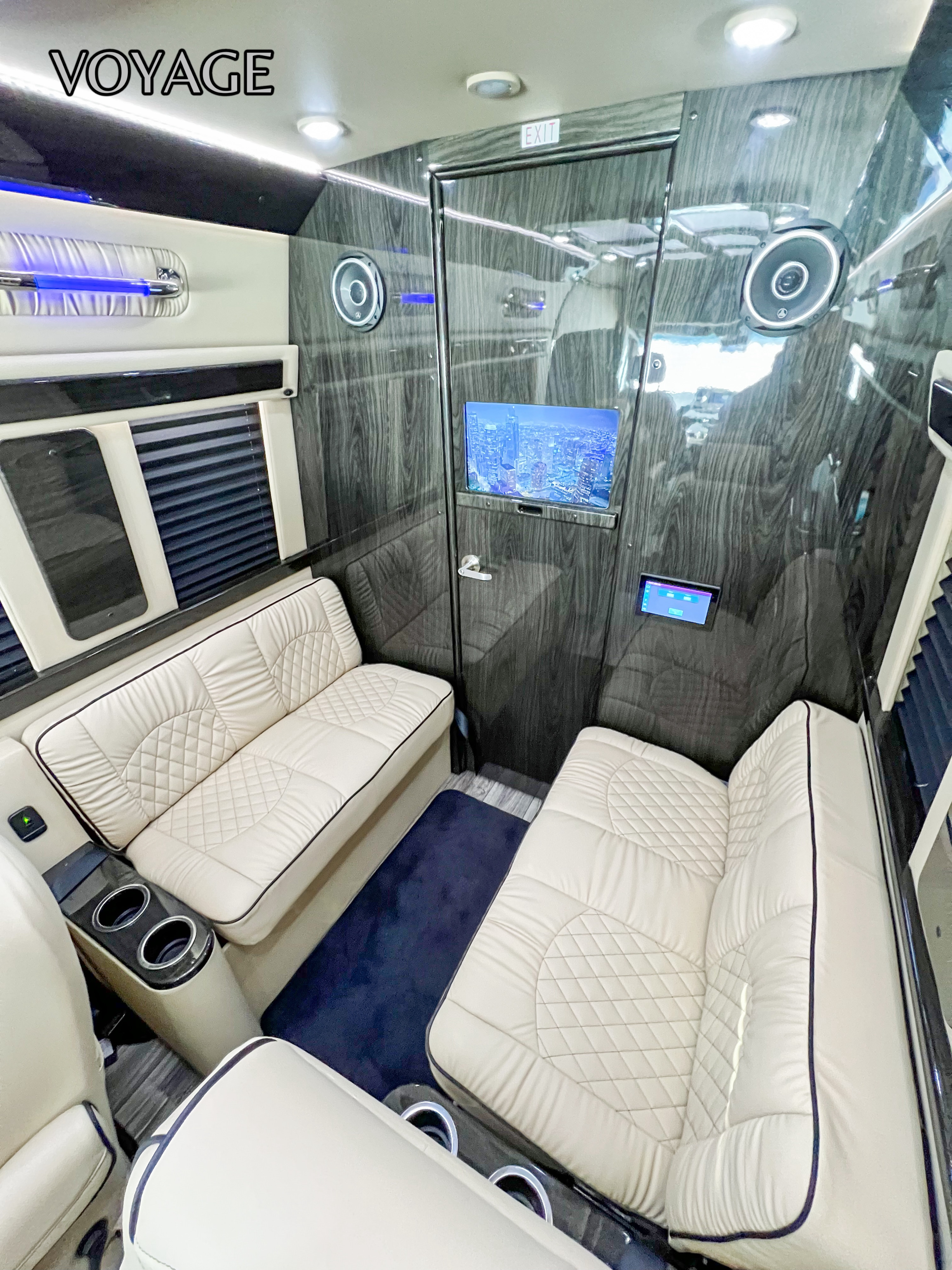 Luxurious RV rental interior: cream quilted seating, wood-grain walls, and an entertainment screen. Perfect for travel.. Mercedes-Benz Sprinter 419 LWB High Roof 2024
