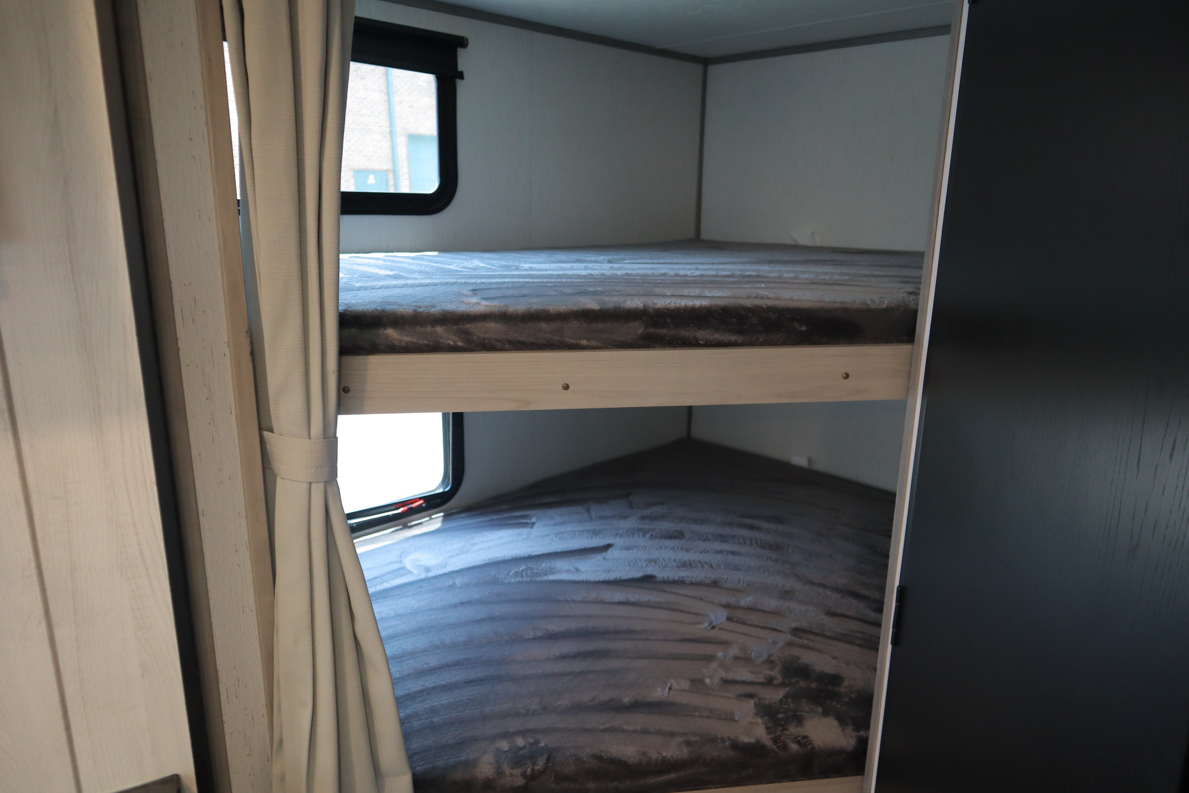Inside this RV rental, two cozy bunk beds with windows and curtains offer comfortable sleeping for camping trips.. Dutchmen Kodiak 2022