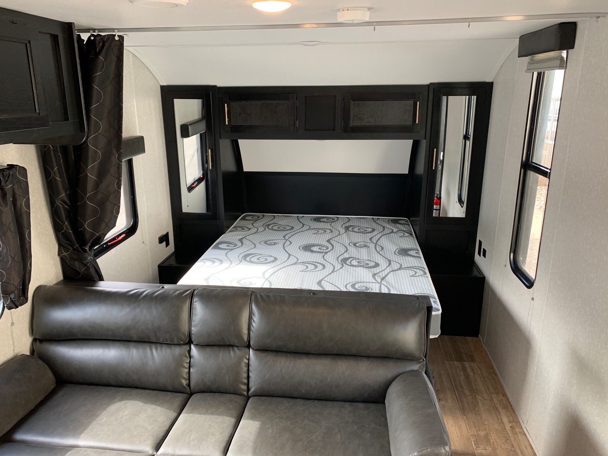 Spacious RV rental interior featuring a comfortable bed with overhead storage, a plush sofa, and wood-look flooring.. Forest River Cherokee Grey Wolf 2022