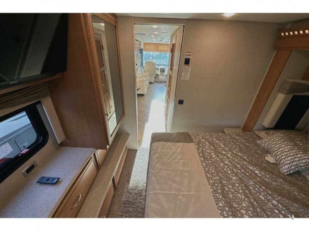 RV rental interior: A cozy bedroom with TV and window, looking into the front living area.. Bay Star Bay Star Motorhome 2018