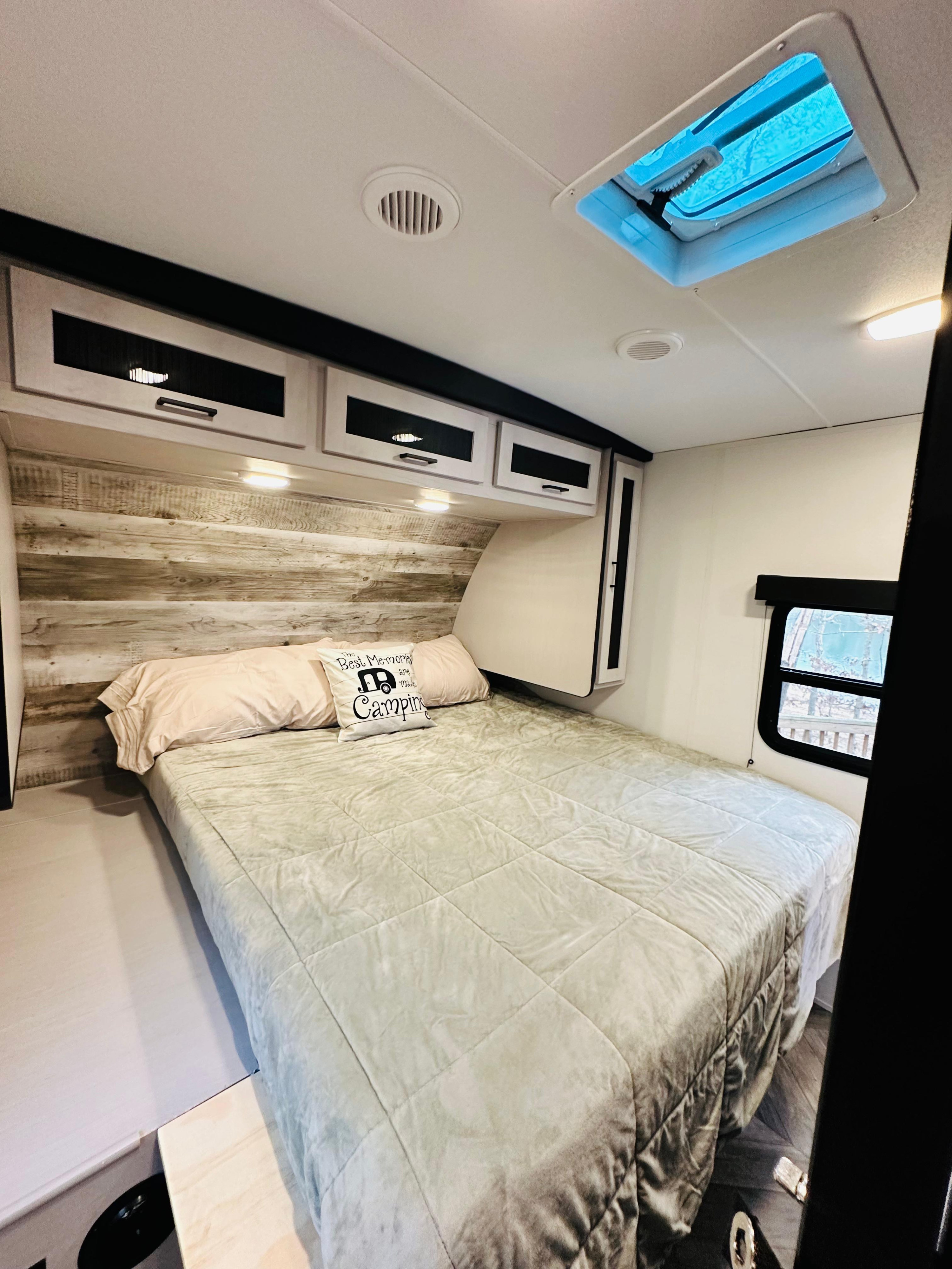 Comfortable RV rental bedroom, featuring a cozy bed, wood headboard, storage cabinets, and a bright skylight.. Heartland RVs Mallard 2024