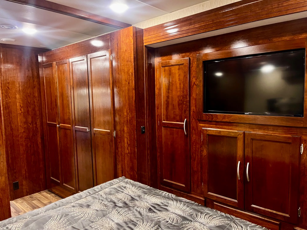 Spacious RV rental bedroom featuring rich wood cabinetry, a built-in TV, and ample storage. Perfect for travel.. Coachmen Mirada 2018