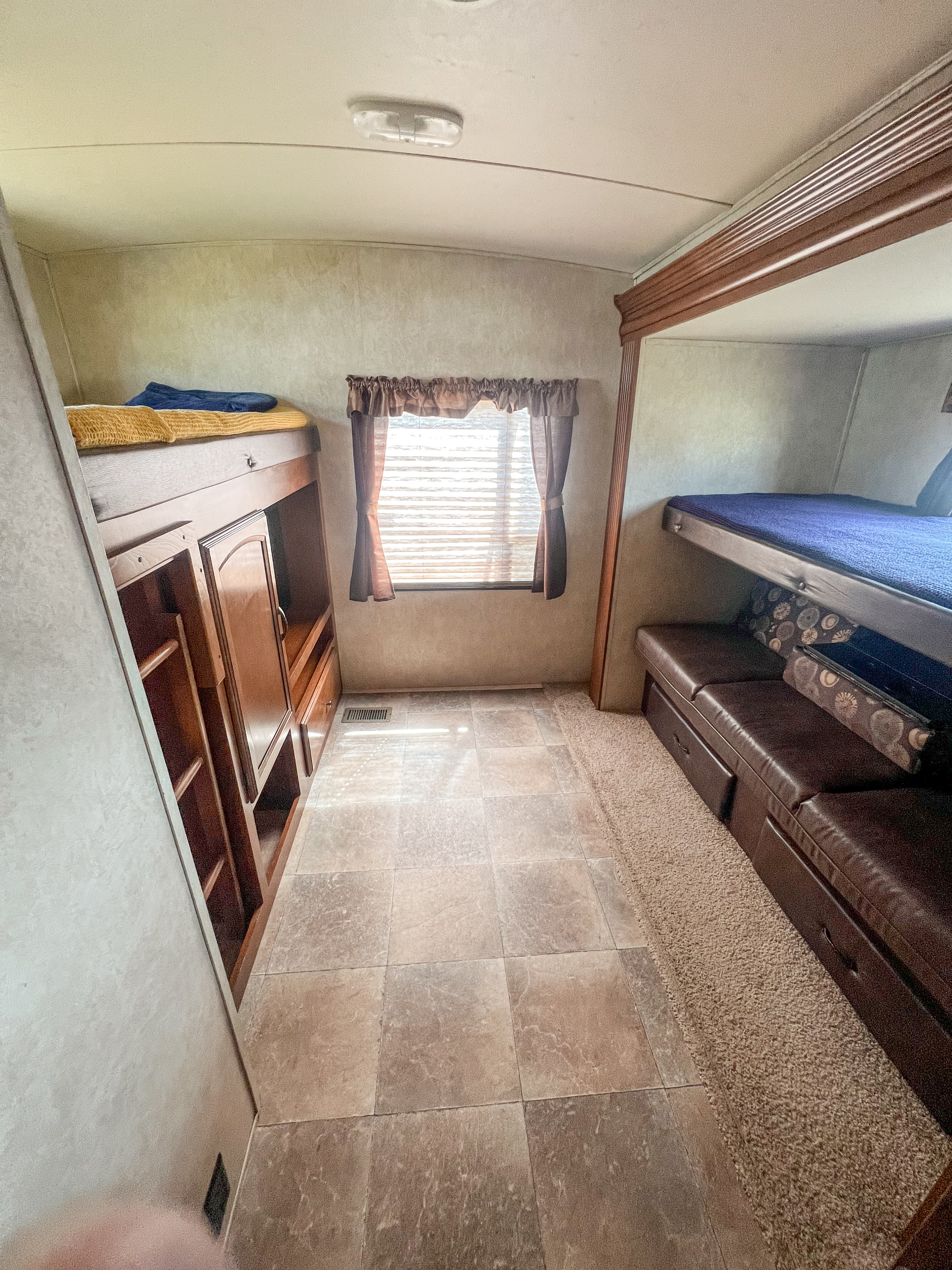 This RV rental interior features a bunk room with two beds, a convertible sofa, and storage, great for families.. Forest River Wildwood Heritage Glen Lite 2013