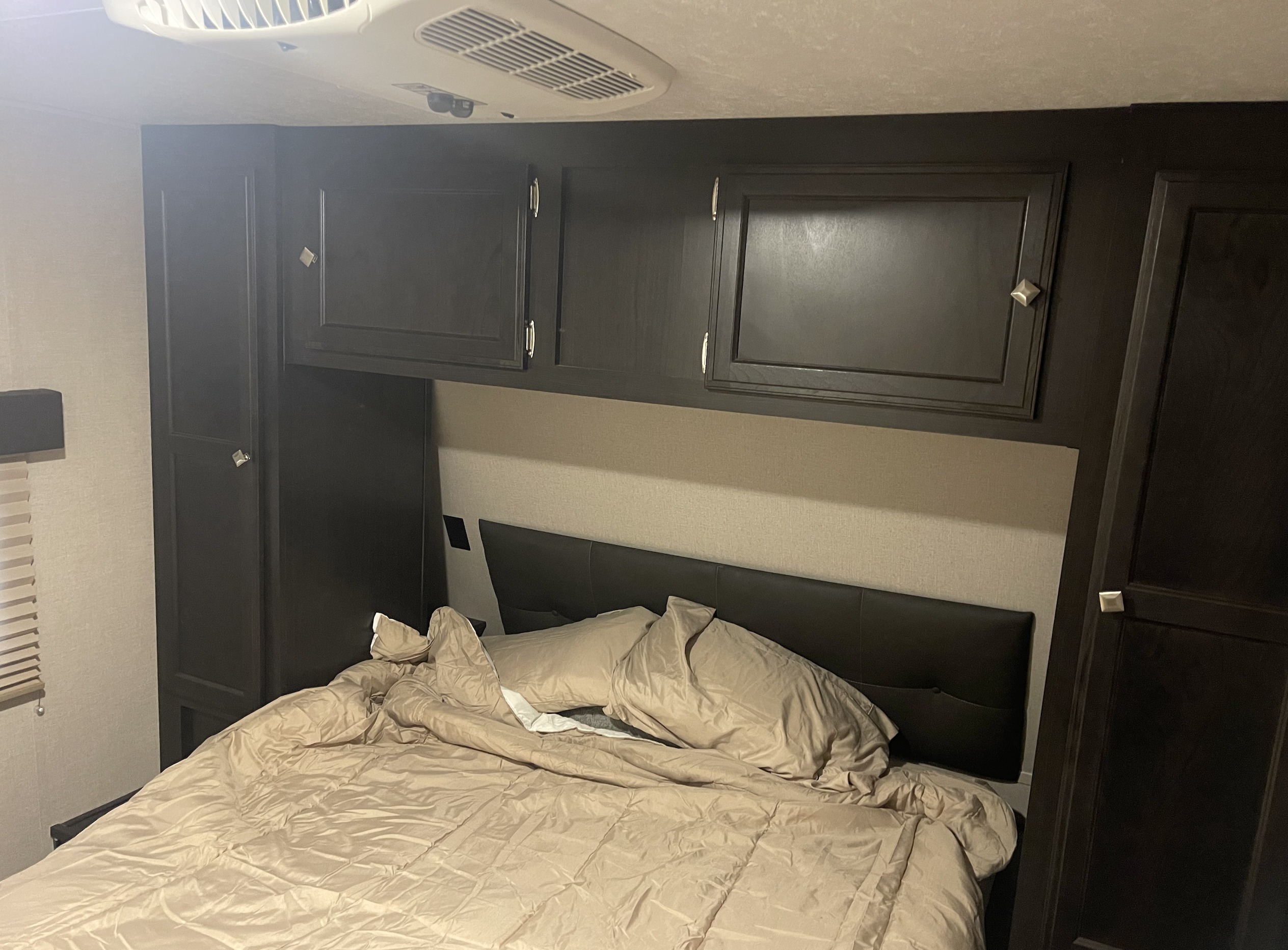 RV rental bedroom featuring a comfortable bed with a dark headboard, overhead cabinets, and an AC unit.. Sport trek 322vrl 2020