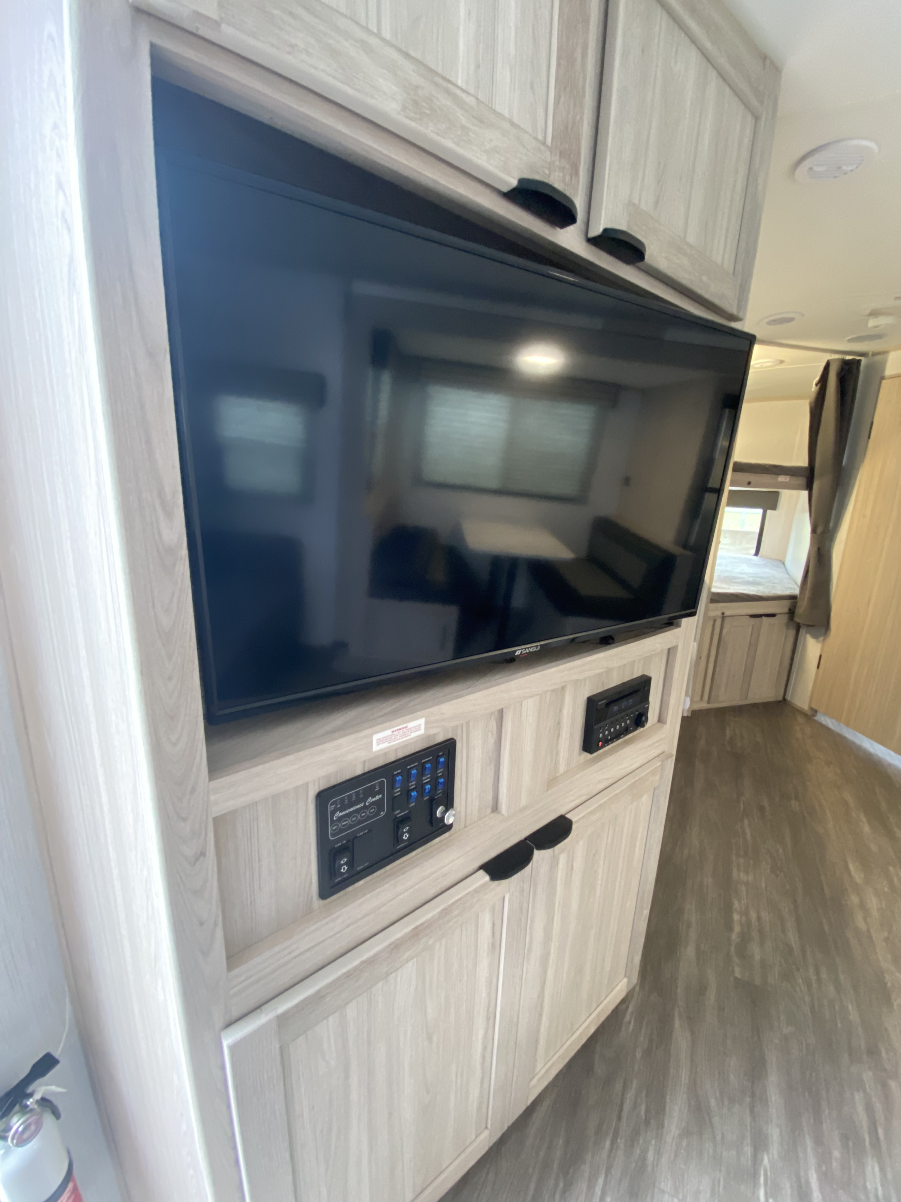 RV rental interior: light wood entertainment center with TV, convenience panel, stereo, and storage. Modern design.. Cruiser RV Shadow Cruiser 2022