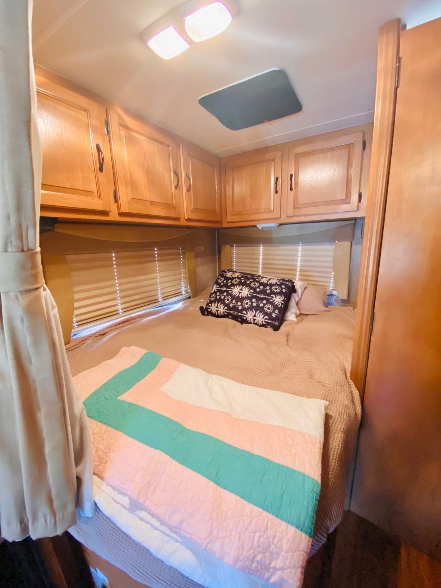Cozy RV rental bedroom featuring a comfortable bed, wood cabinets, and an overhead skylight.. Forest River Coachmen Prism 2014