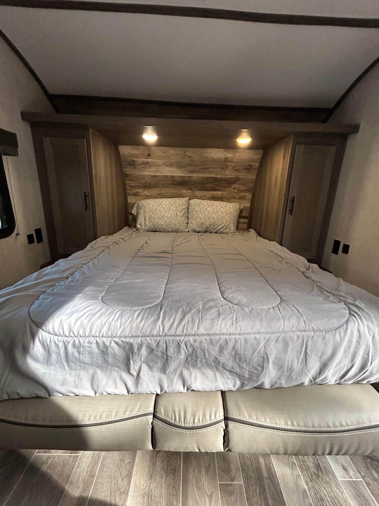 RV rental interior: a cozy bedroom with a comfortable bed, wood headboard, lighting, and side cabinets. Great for trips.. Gulf Stream Ameri-Lite 2022