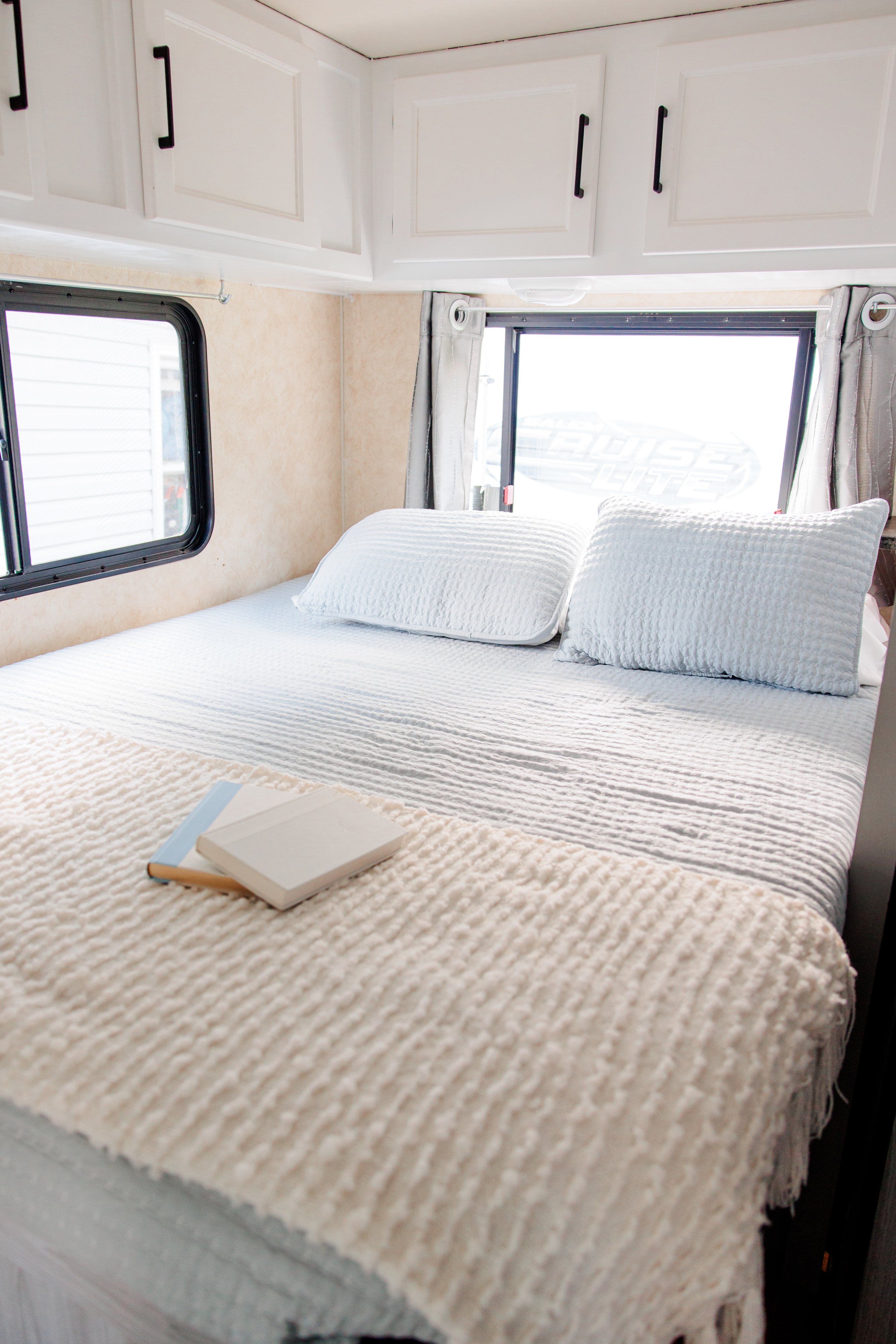 Cozy RV rental bedroom with clean linens, overhead cabinets, and bright windows for a comfortable stay.. Forest River Coachmen Freelander 2012