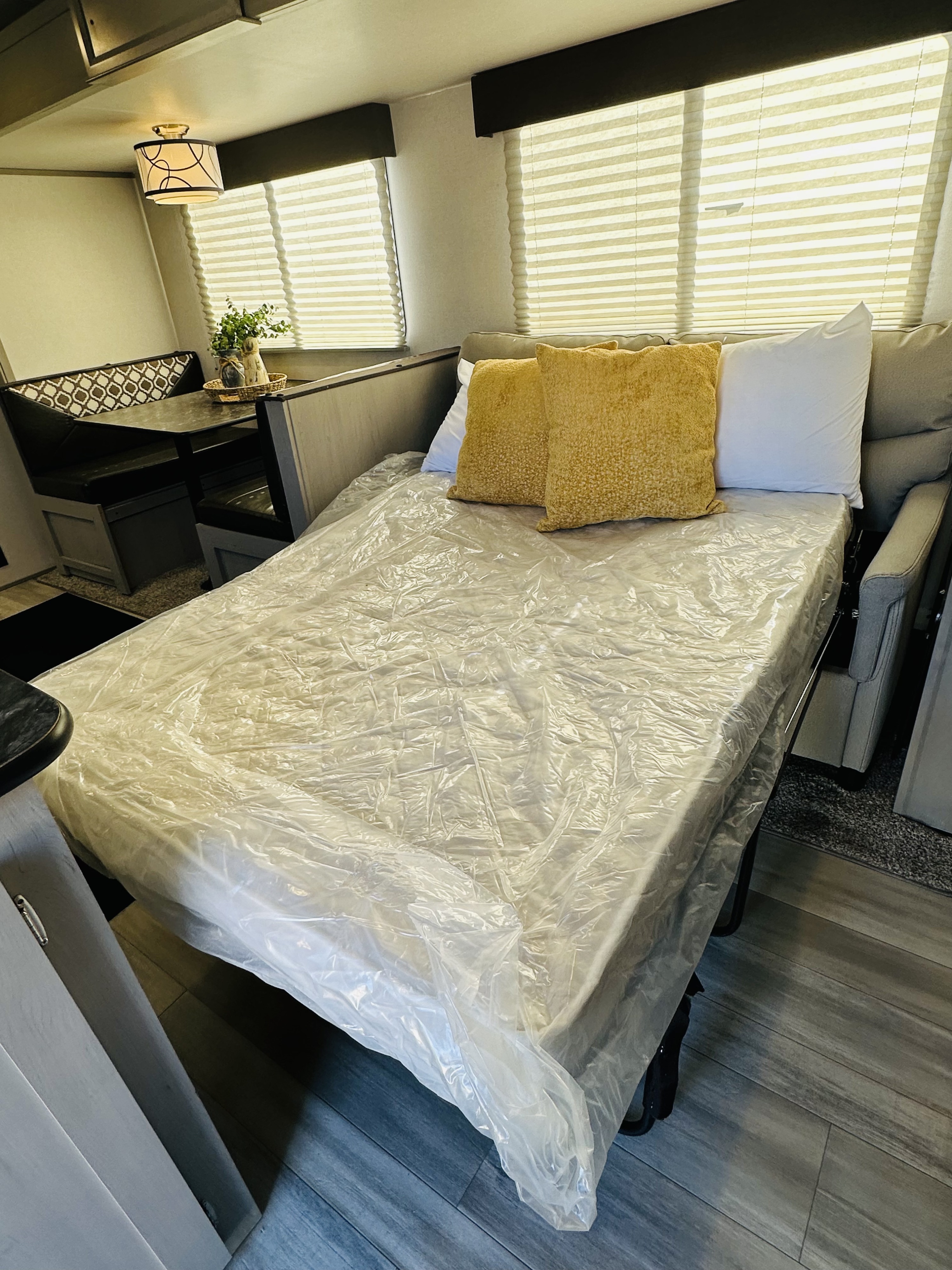 RV rental interior: A clean, plastic-wrapped sofa bed and cozy dining booth await your adventures.. Forest River Tracer LE 2021