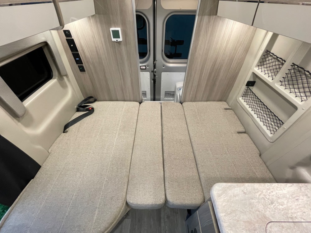 RV rental: Interior showing a flexible bed/seating area in a camper van. Controls & storage visible.. Thor Scope 18G 2024