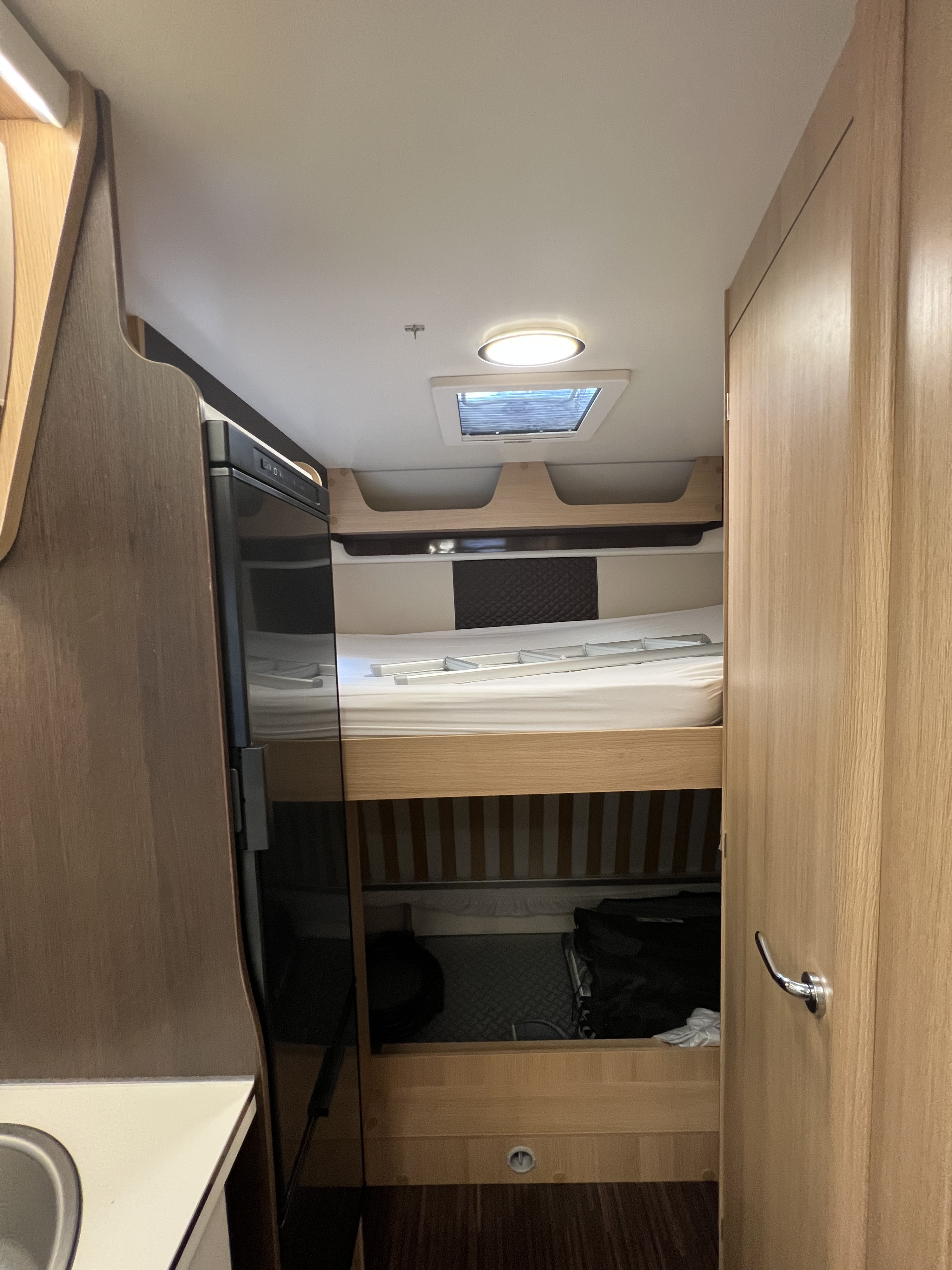 RV rental interior: cozy bunk beds with ladder, refrigerator, and overhead skylight, perfect for family travel.. McLouis Glamys 2023