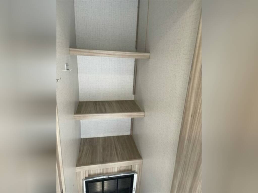 RV rental interior: A narrow closet with three light wood shelves and a vent below offers essential storage.. Winnebago 2301BHS 2022