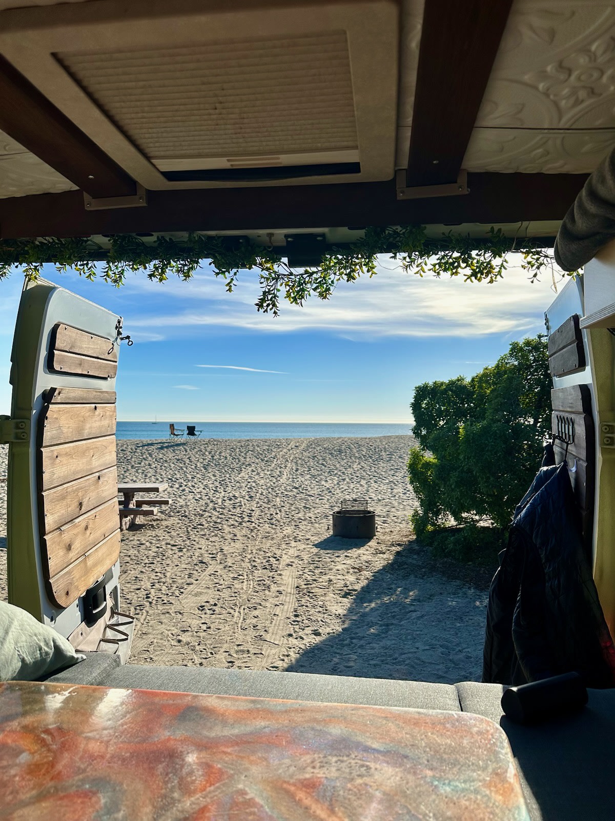 Oceanfront RV rental view: Relax from your camper van at the beach! Sandy shore, chairs, fire pit, and sea beyond.. Custom Ram Promaster 3500 2019