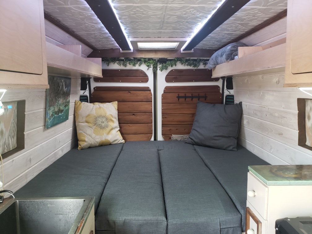 Cozy camper van interior, perfect for your next RV rental trip. Features a convertible bed, kitchenette, and storage.. Custom Ram Promaster 3500 2019