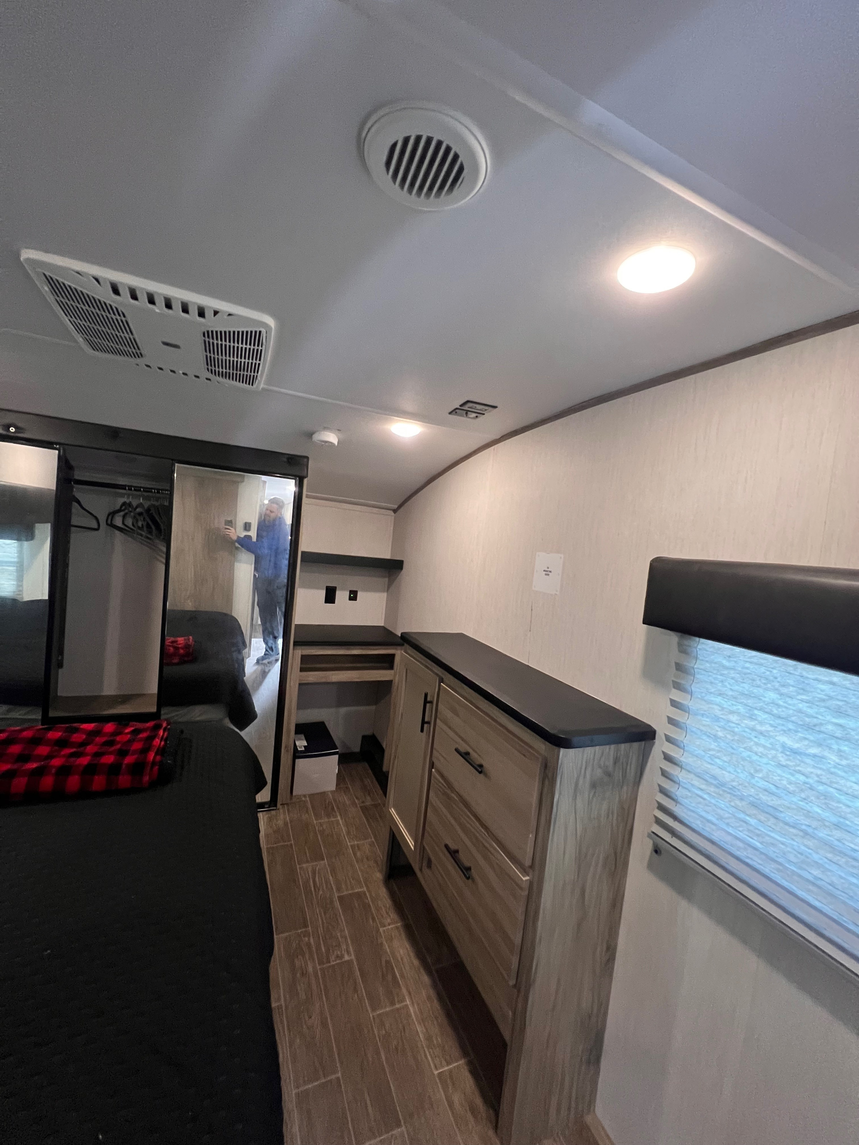Spacious RV rental bedroom with a comfortable bed, mirrored closet, built-in dresser, and modern amenities like AC for your journey.. Forest River Cherokee Arctic Wolf 2022