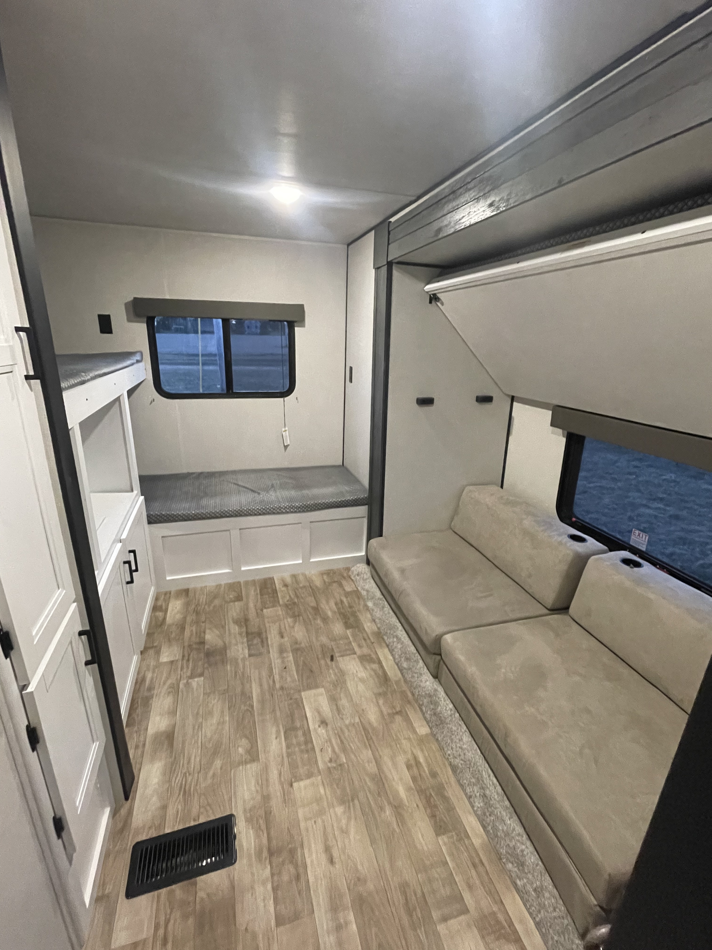 This RV rental interior features bunk beds, sofa seating with cupholders, and wood-look flooring for a functional camper living space.. Keystone RV Hideout 2022