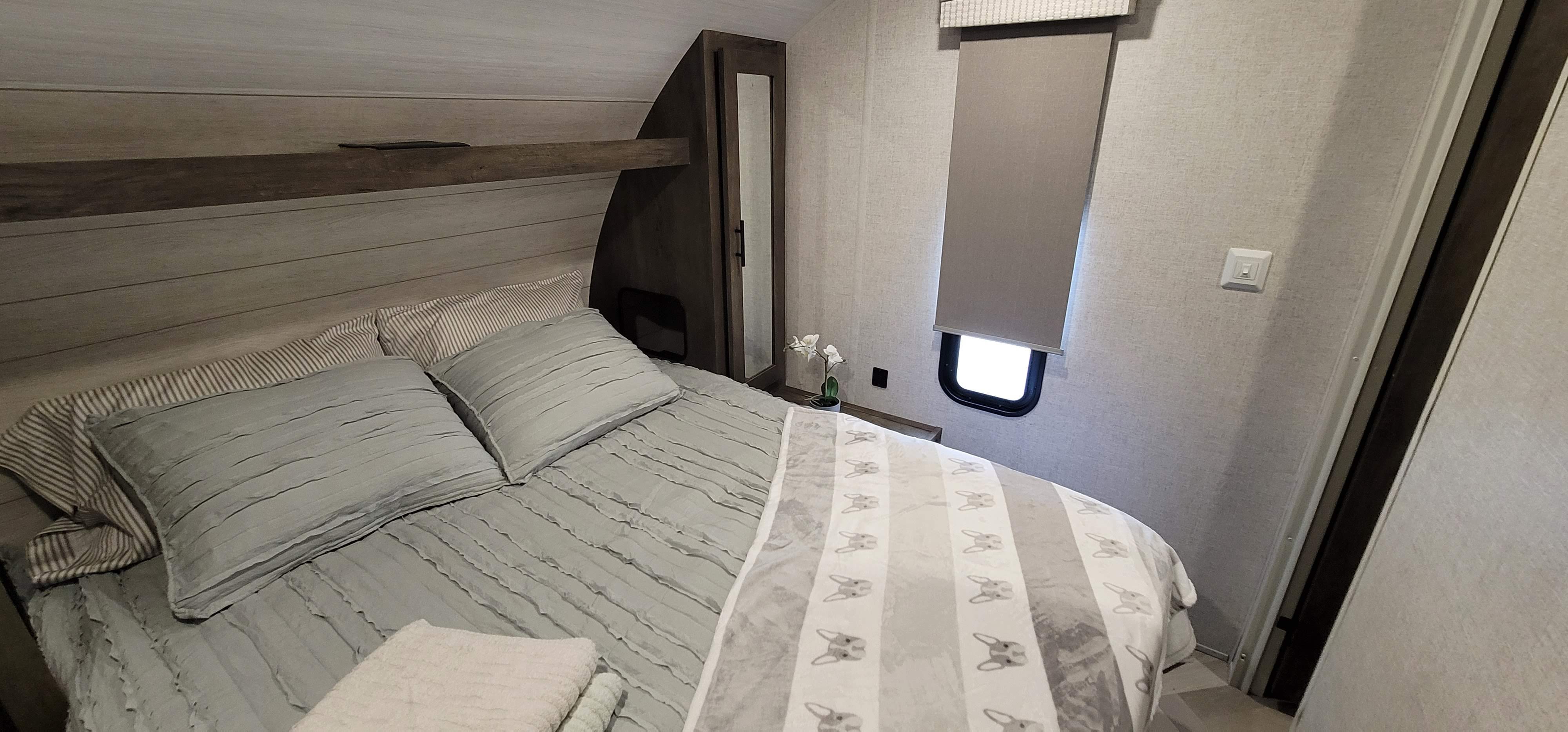 Comfortable RV rental bedroom: cozy bed, light wood headboard, mirrored cabinet, and small window.. Forest River Salem Cruise Lite 2021